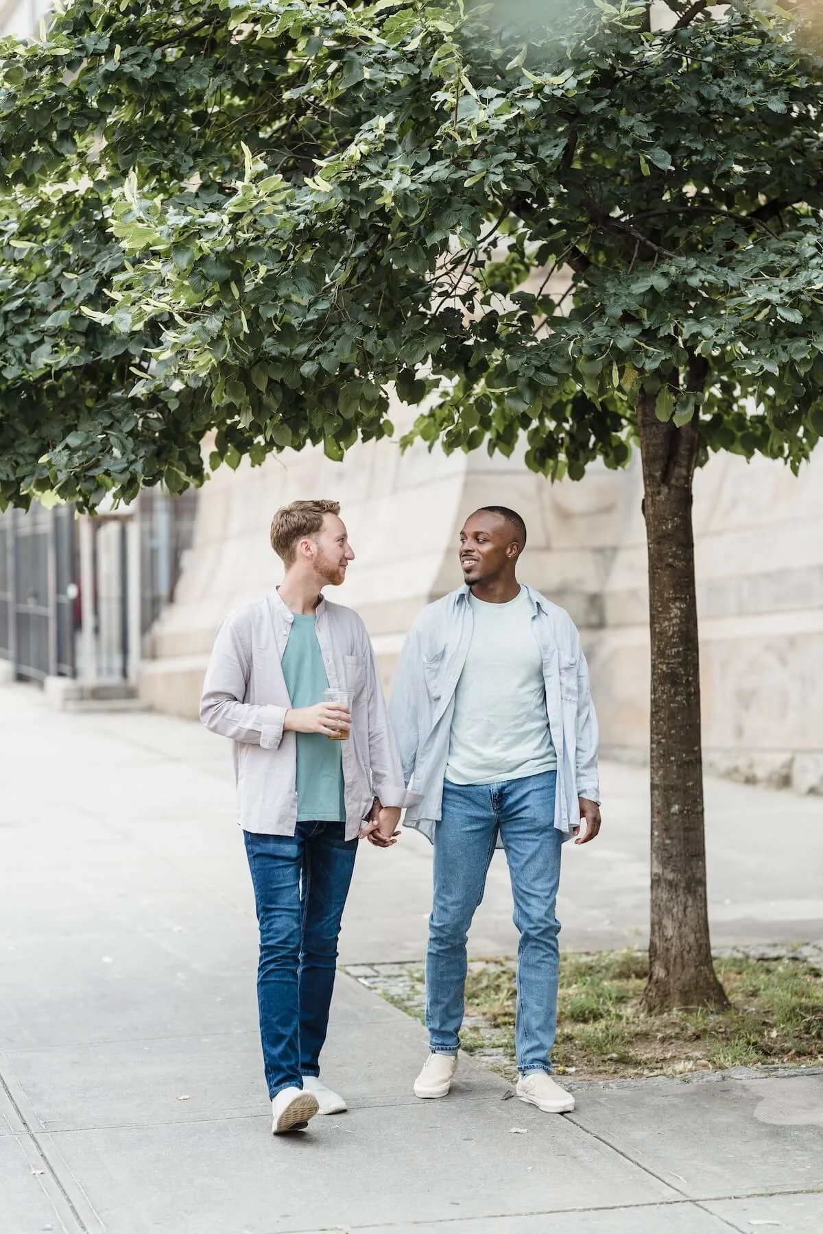 Two male partners walk hand in hand and share a conversation, reflecting the ease and security of a strong couple bubble that couples therapy in St. Louis and a St. Louis couples therapist help partners build and protect.