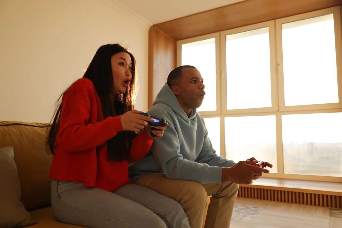 A couple plays video games together on the couch, sharing a moment of playful engagement that reflects the everyday connection a St. Louis couples therapist helps partners notice and protect through couples therapy in St. Louis, MO.