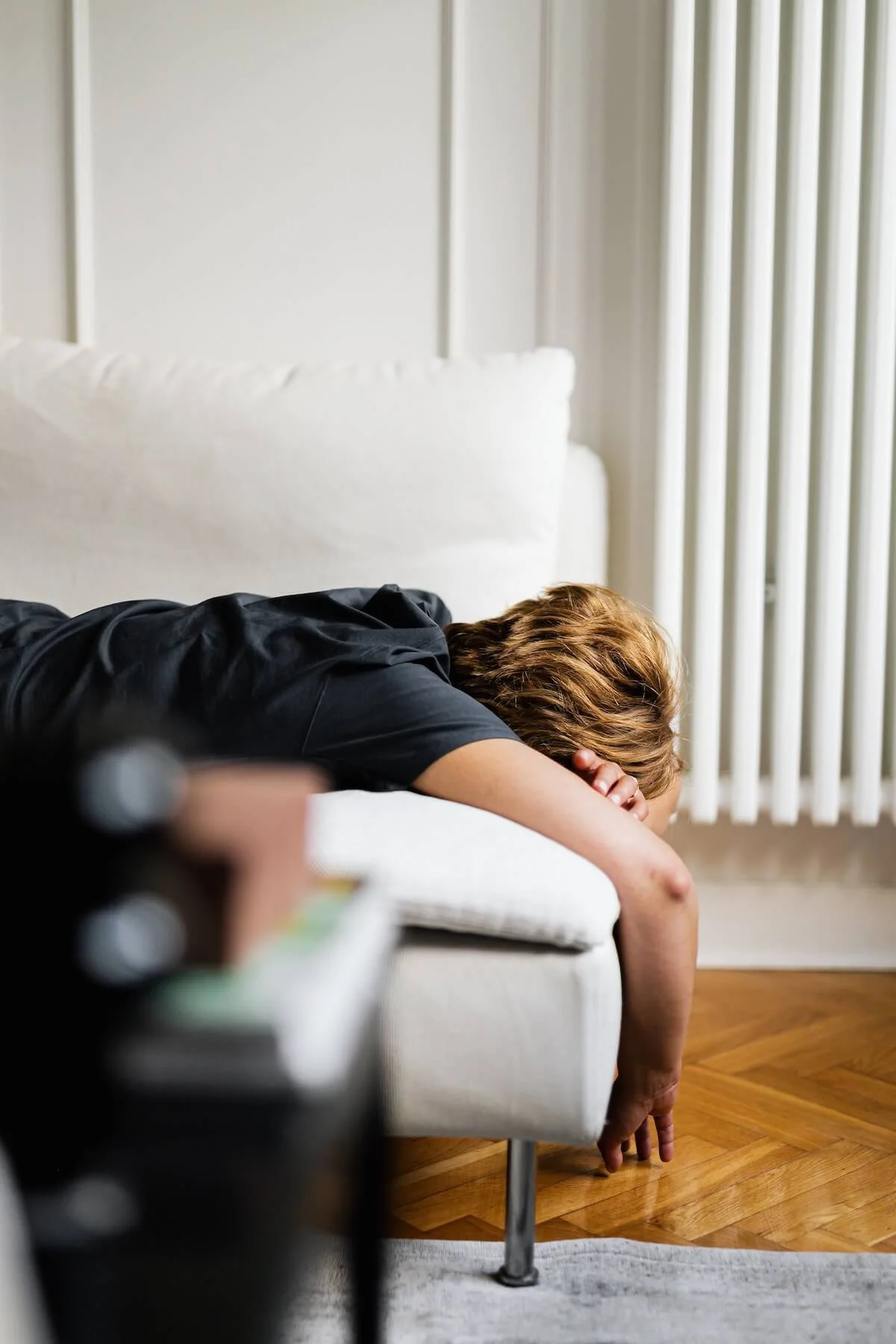 A person slumps face-down over the arm of a couch in exhaustion, capturing the kind of chronic fatigue that a Functional Medicine Doctor in St. Louis, MO investigates through St. Louis Functional Medicine care.