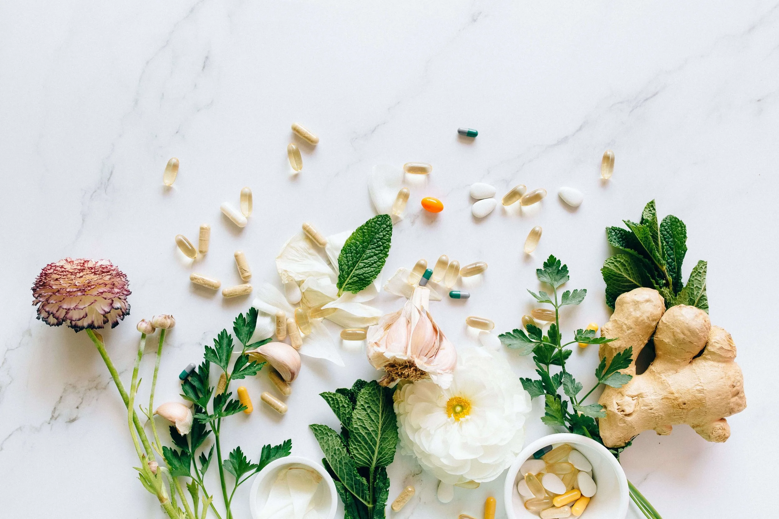 A mix of pills, herbs, and ginger on a marble countertop. Representing the core of St Louis functional medicine. Where a holistic doctor combines both western medicine and other naturopathic methods to get you feeling better.