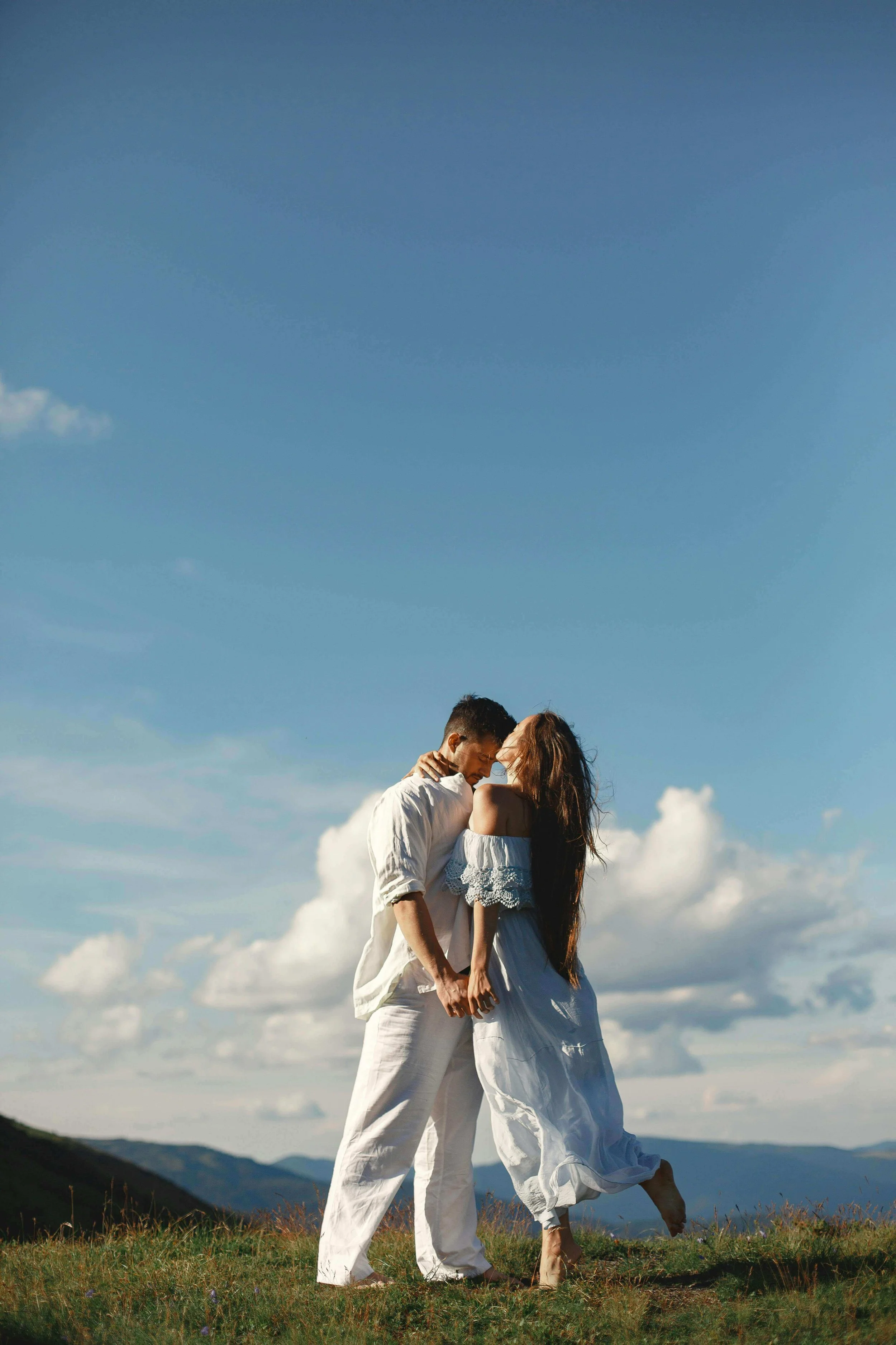 A couple in flowing white clothing on a sunlit hilltop. Are you and your partner struggling to connect? IFS Couples counseling in St. Louis, MO, can help to promote healing from within so you can reach each other again.