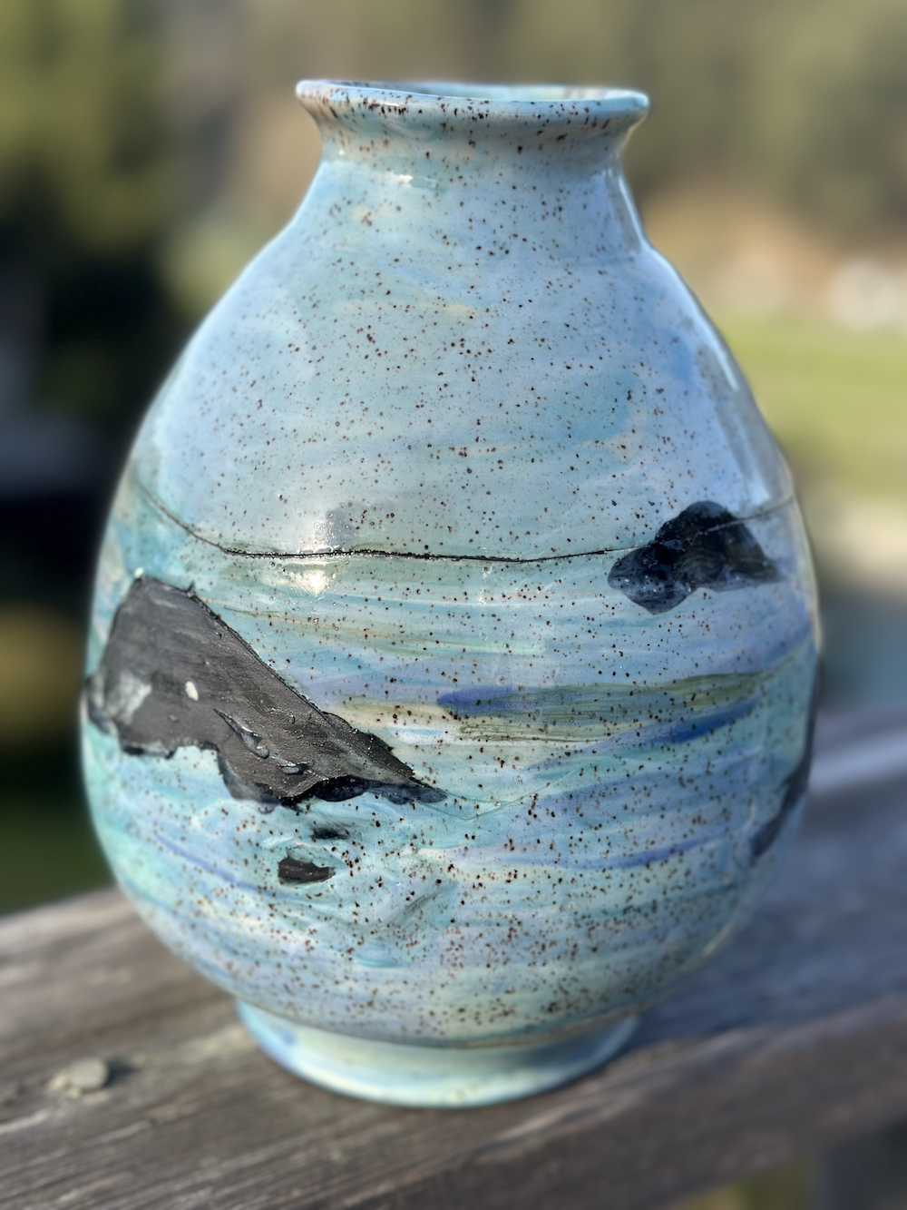 Ceramic vase with ocean scene depicting waves, rocks, and a whale, glazed in blue and black