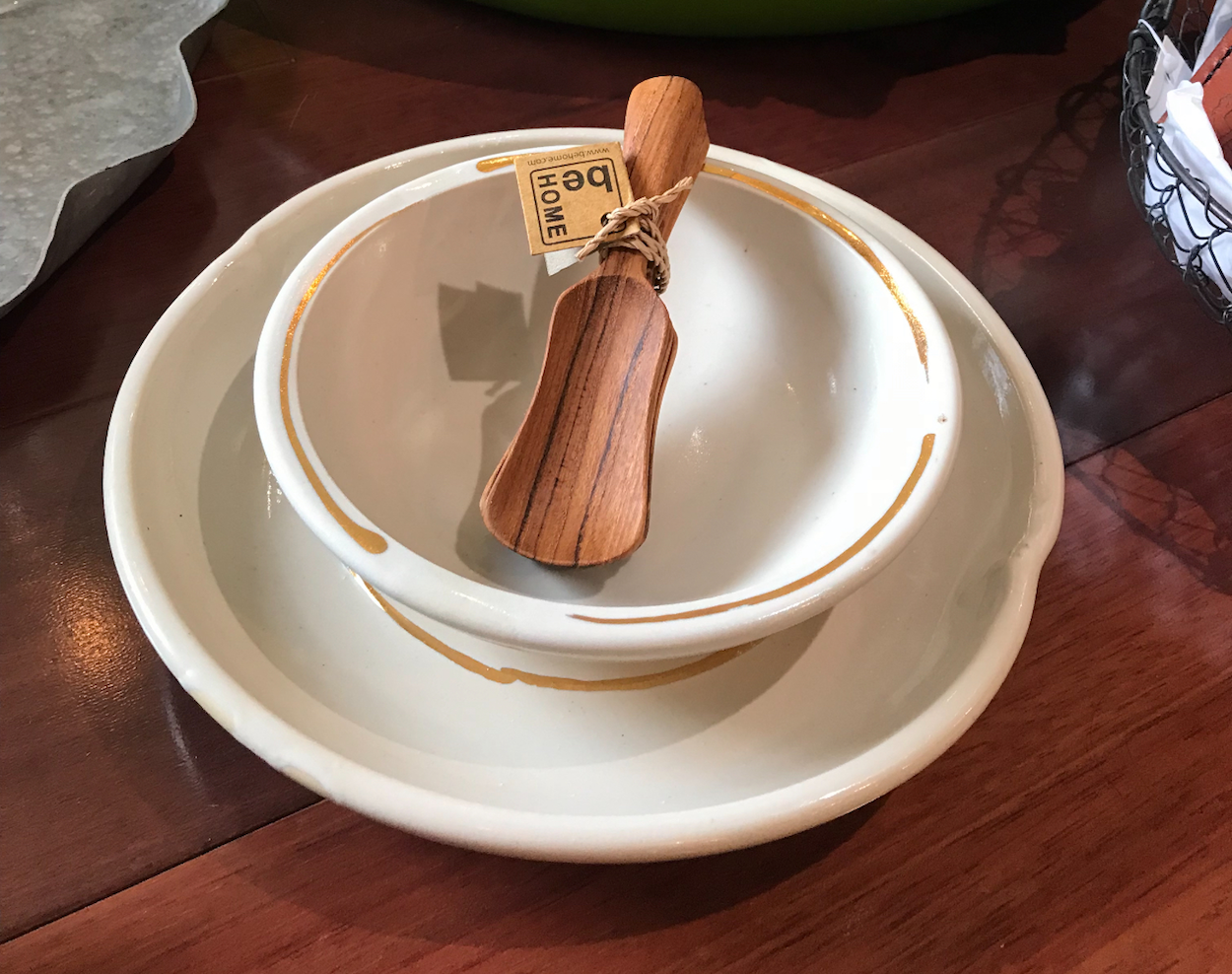 Two ceramic bowls stacked on a wooden table with a wooden rolling pin and a small tag attached to it in the top bowl.