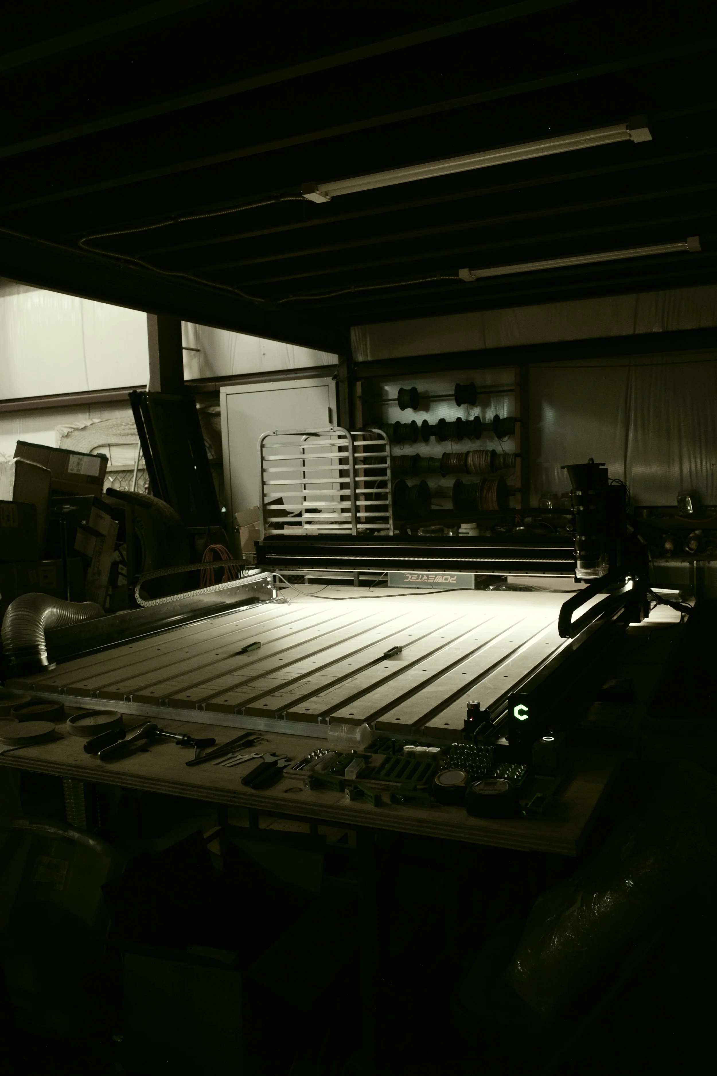 A workspace with a laser cutter, tools, and supplies in a workshop or factory setting.