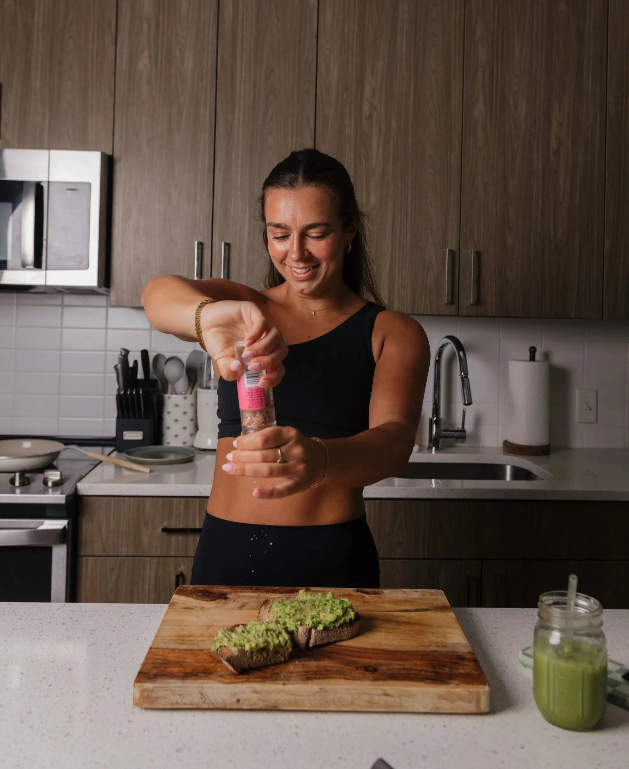 A woman preparing avocado toast in a modern kitchen.