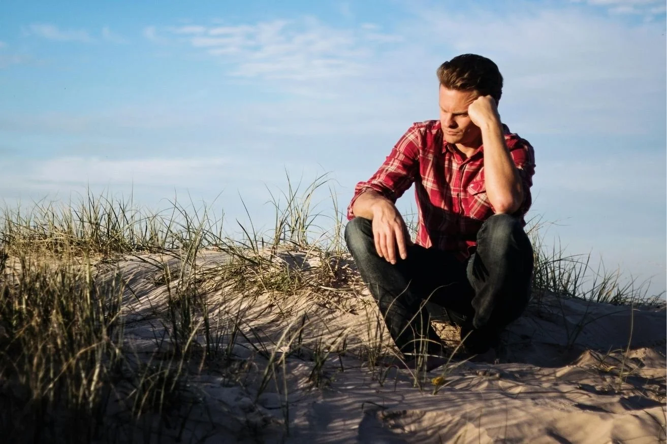 Young man sitting and contemplating on the beach