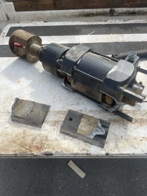 An industrial electric motor and two metal blocks on a work surface.