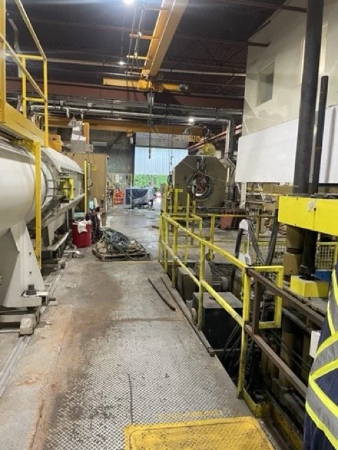 Industrial factory interior with machinery, yellow safety railings, and tools.