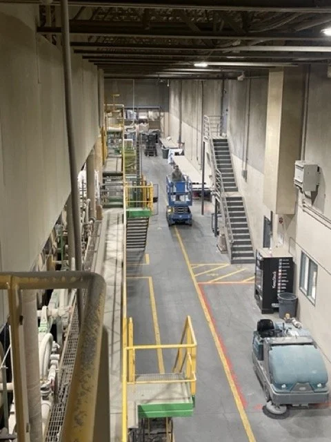 Industrial warehouse or facility with stairs, utility equipment, and cleaning cart.