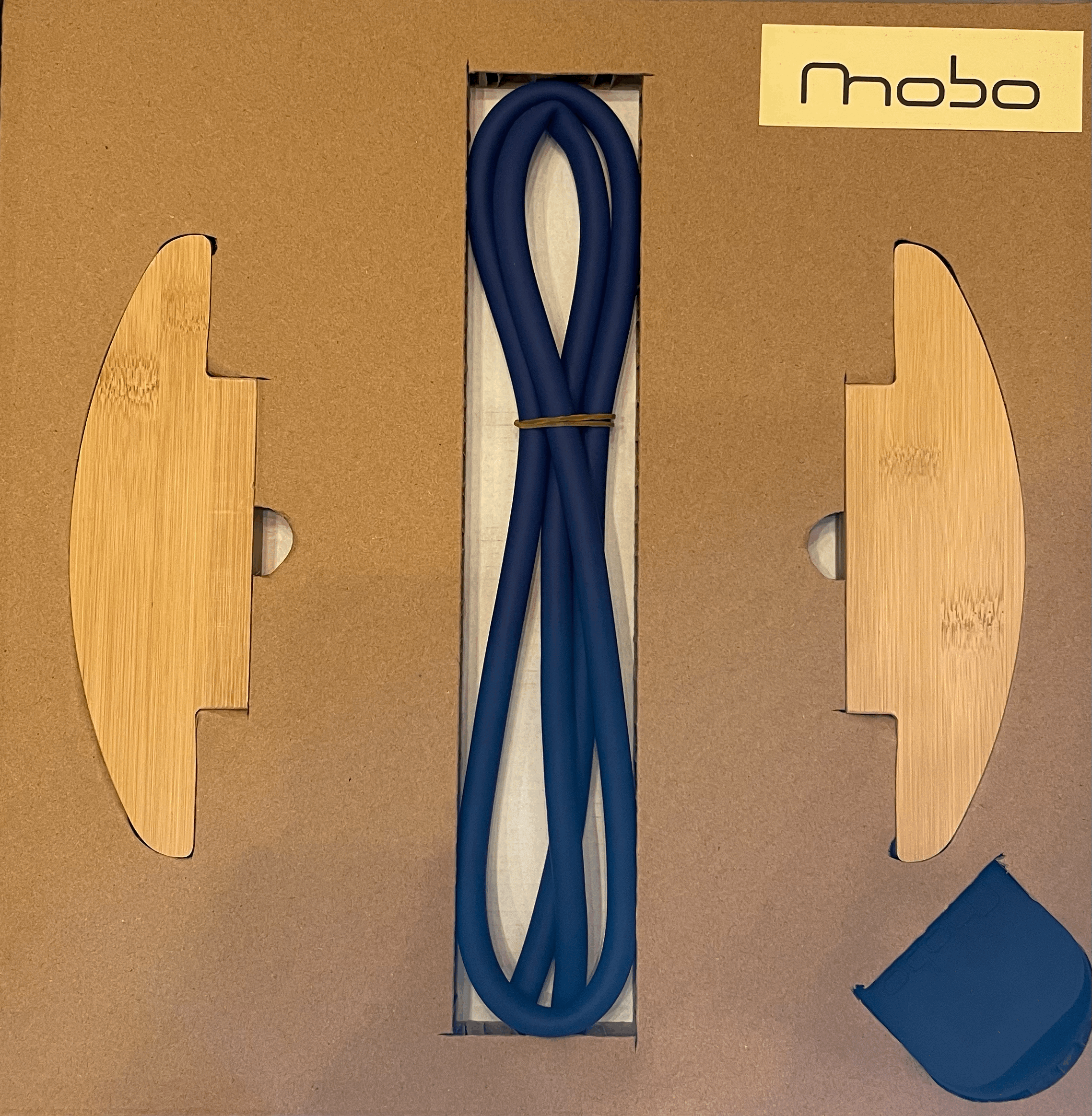 Blue swimming fins in a cardboard box with wooden inserts, a black shoelace, and a small black item in the bottom right corner, and a yellow label with black text reading 'mobo'.