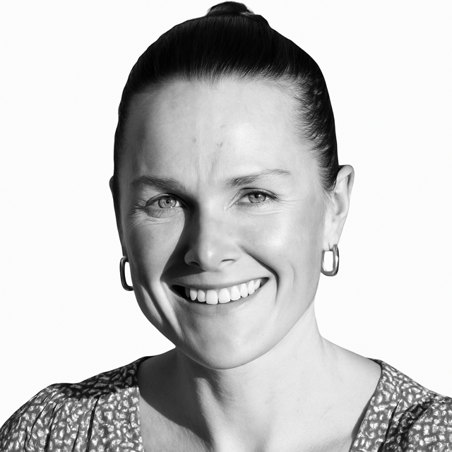 Black and white portrait of a smiling woman with her hair in a bun, wearing hoop earrings and a dotted top.