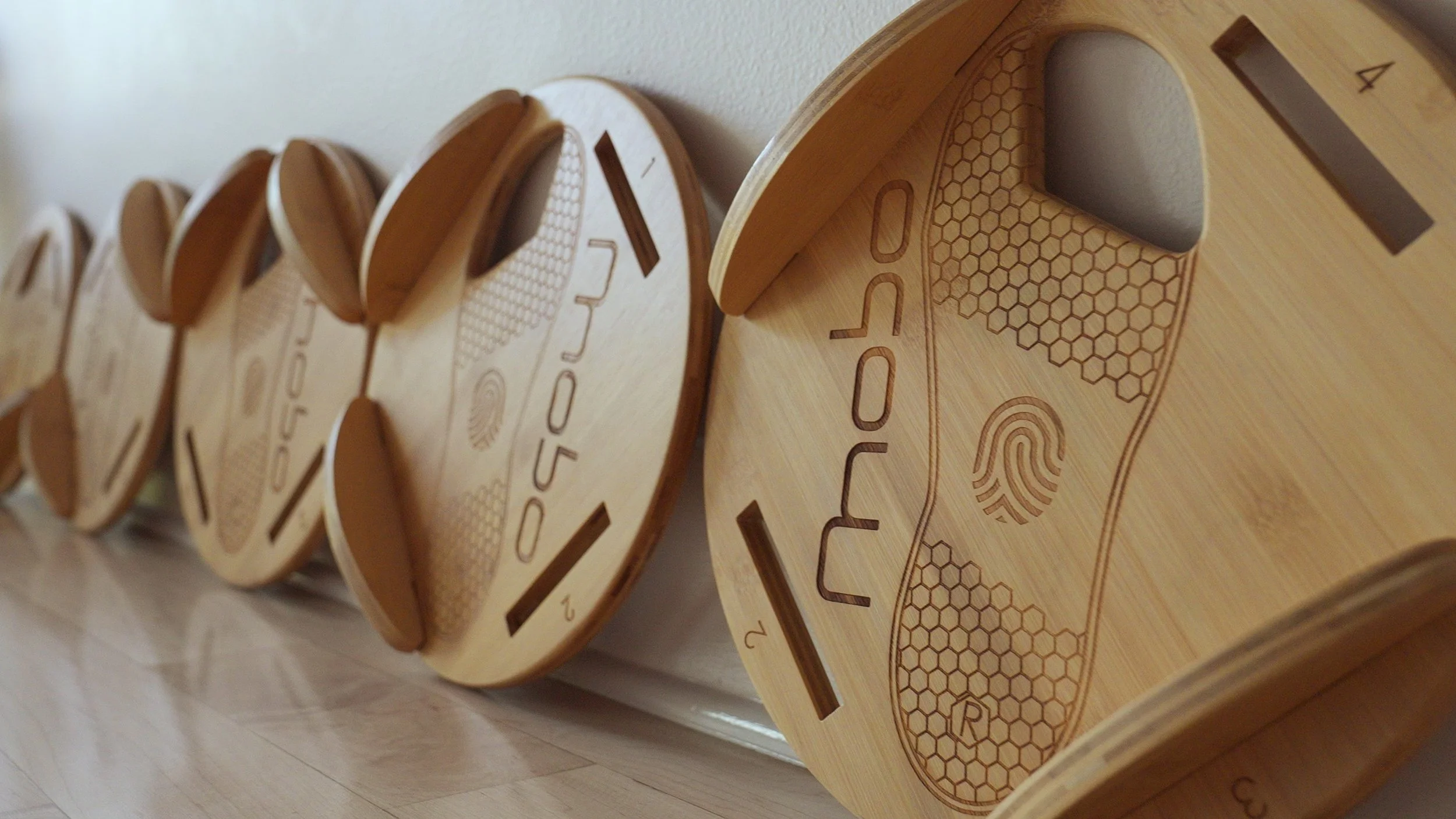 A row of round, wooden signboards with engraved designs and text, leaning against a wall.