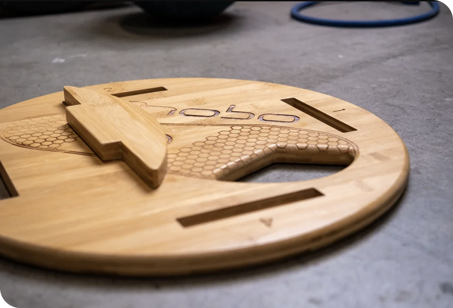 Close-up of a wooden game board with a honeycomb pattern and carved lines, placed on a gray surface.