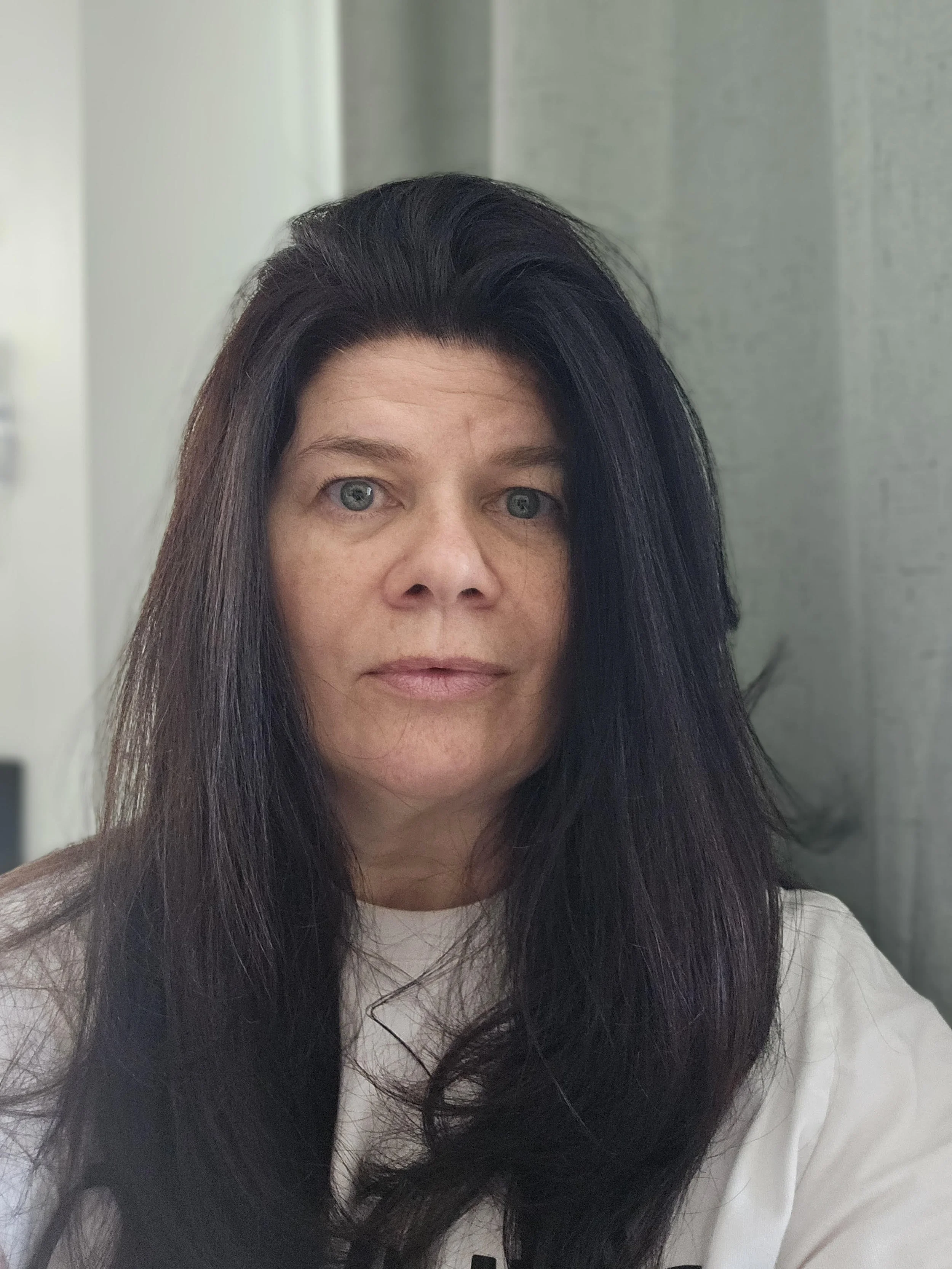 Close-up of a woman with light skin, blonde hair, and blue eyes smiling, against a blue background.