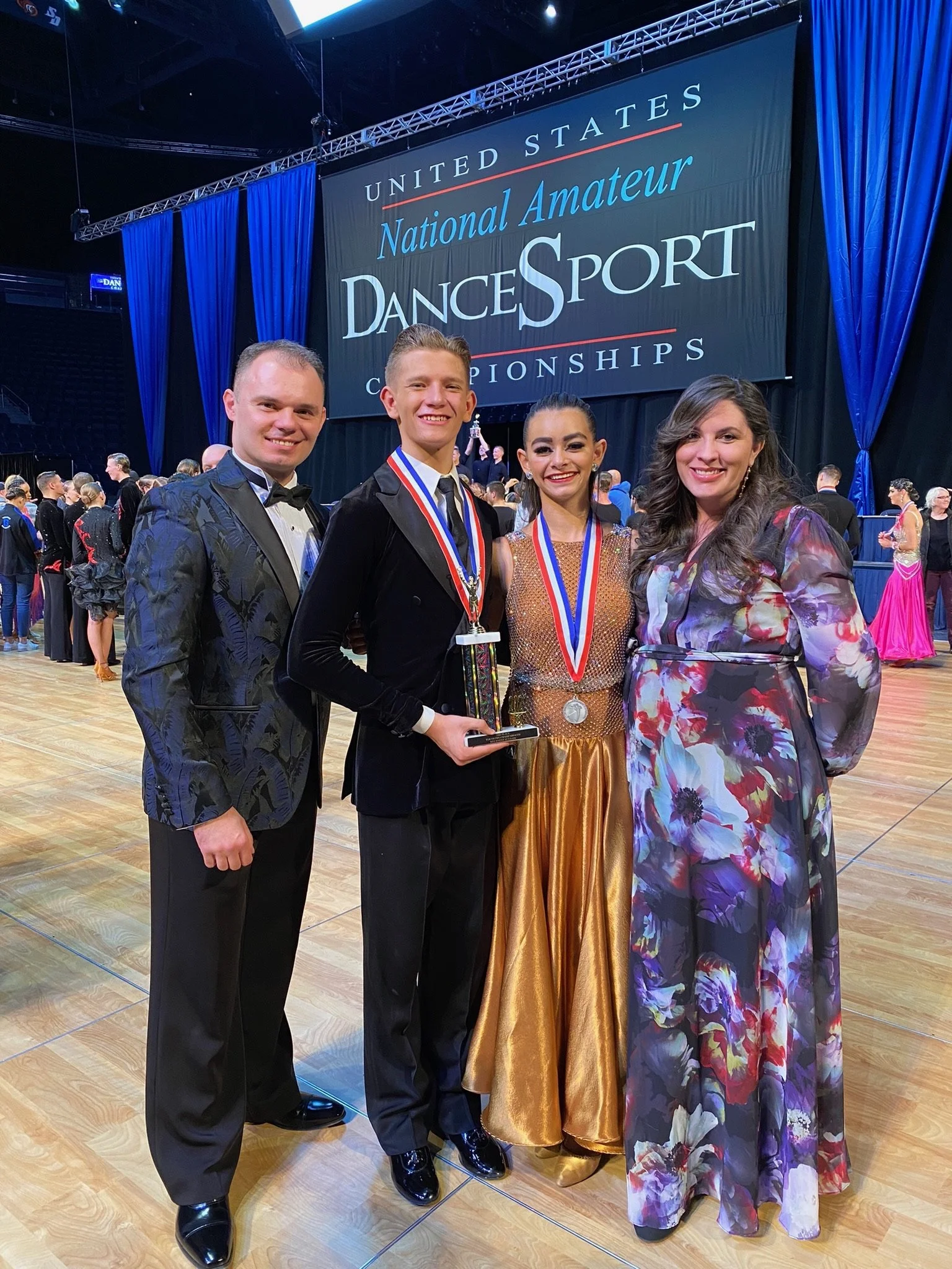 Noah Scribner standing with his Smooth Ballroom coaches after winning an event at the National Amateur DanceSport Championship competition hosted at BYU.