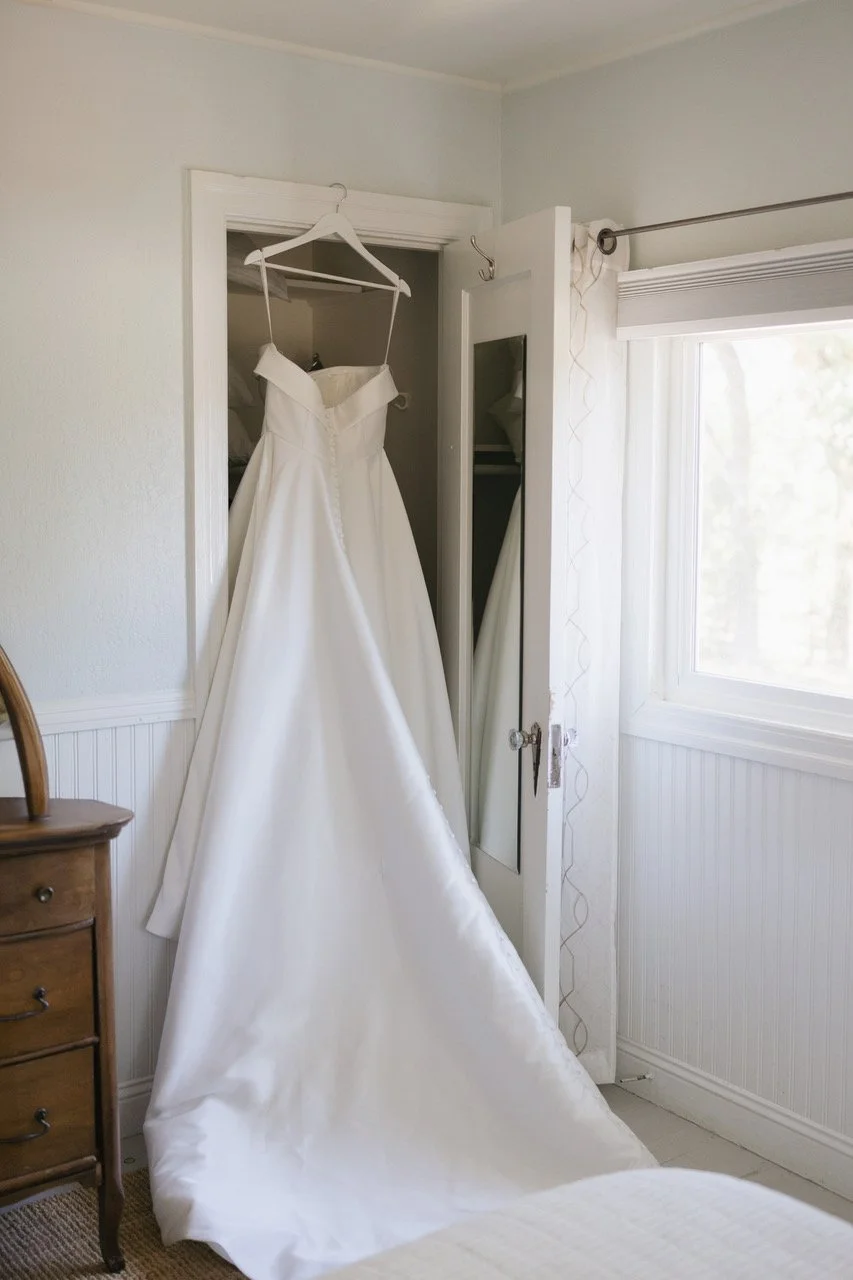 white wedding dress hanging on a hanger in a closet