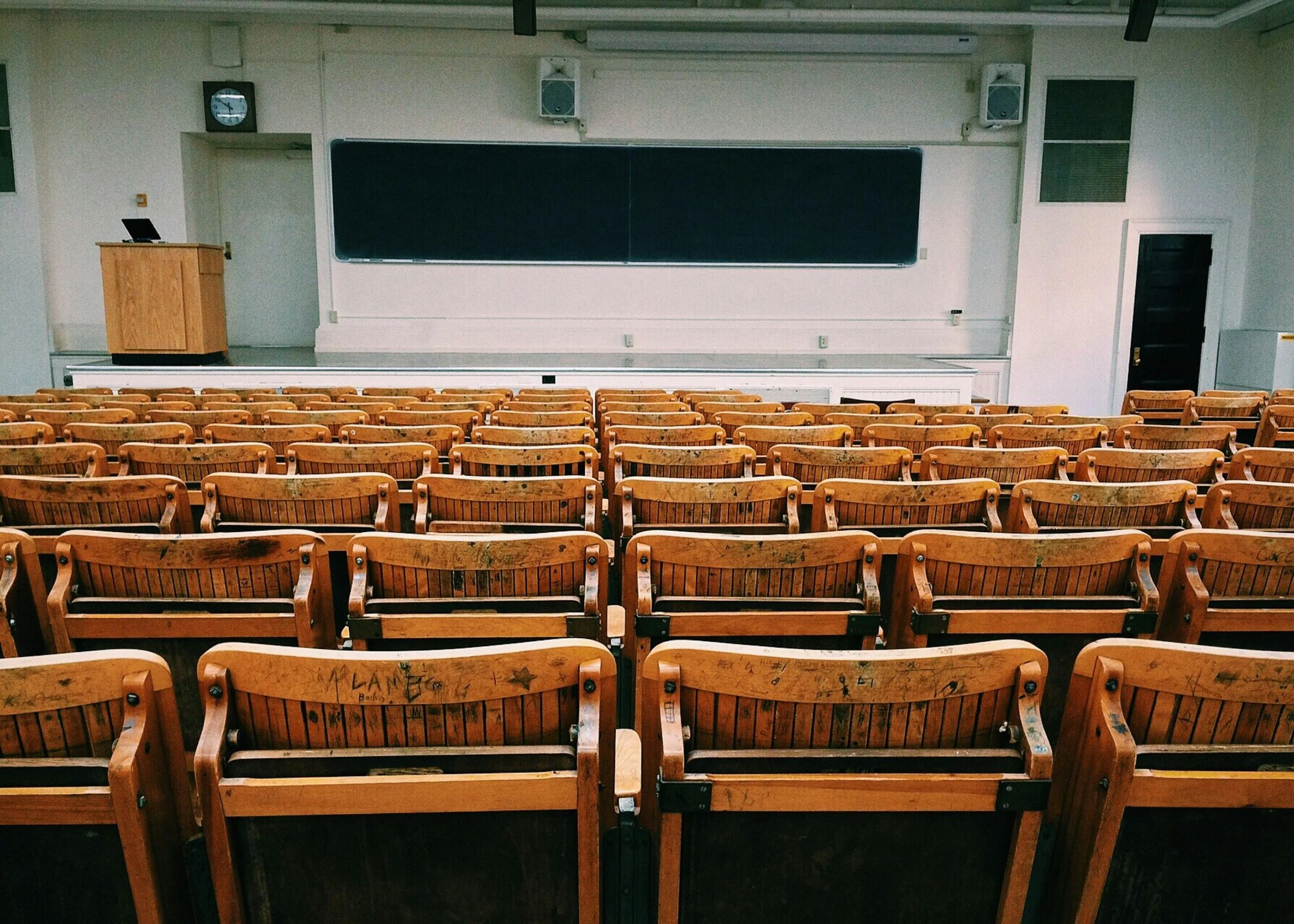 Empty wooden chairs facing the front of a lecture hall. Representing the insights of Bernie Burk Law Professor on ethical preparedness in legal education.