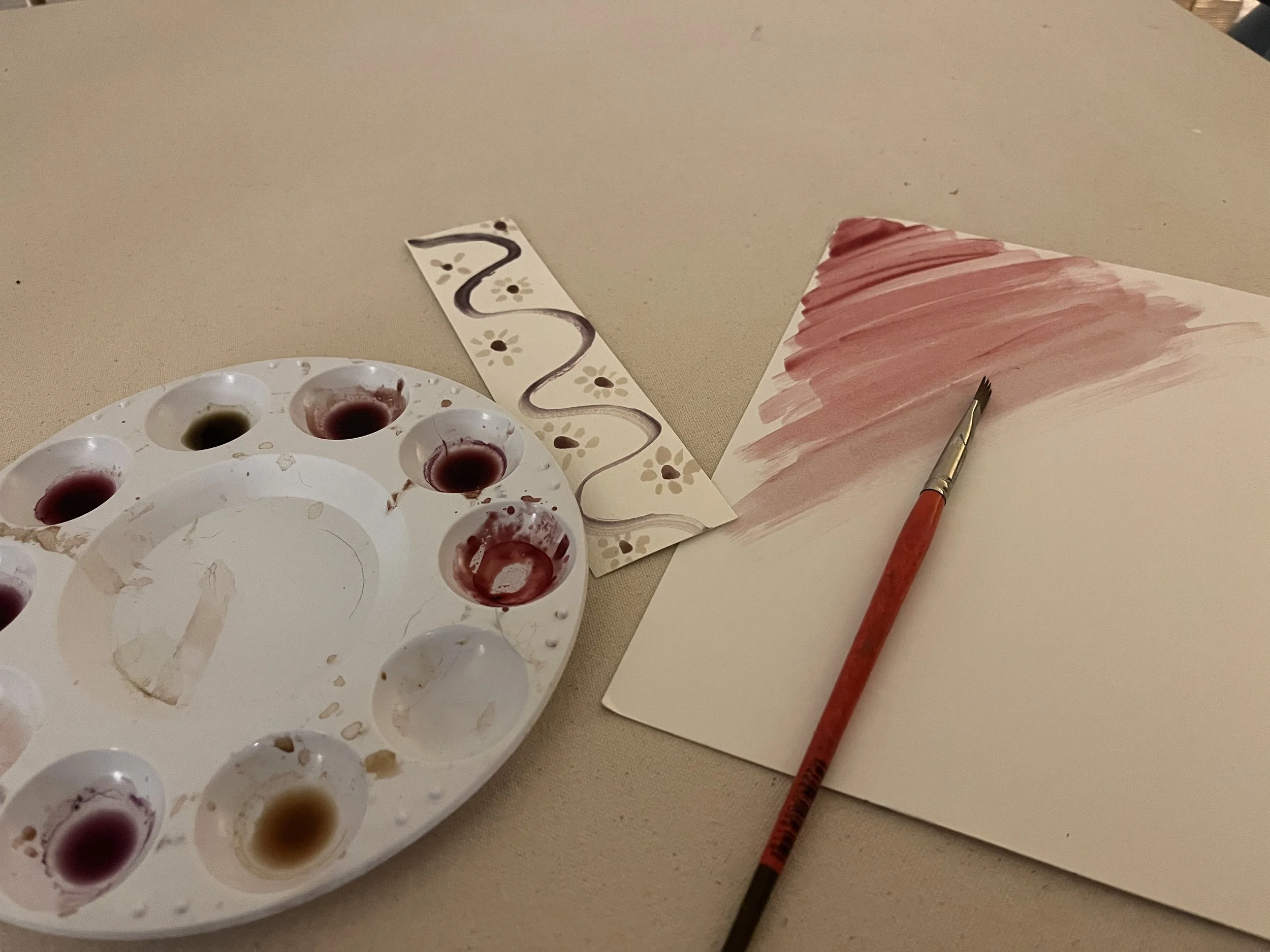 Paint palette, brush and paintings on a canvas background