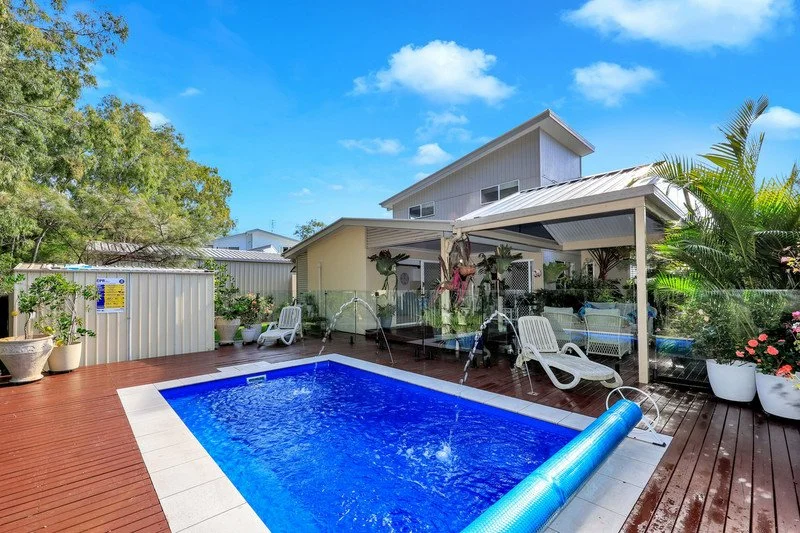 Backyard with a swimming pool, pool cover, lounge chairs, potted plants, and a backyard shed.