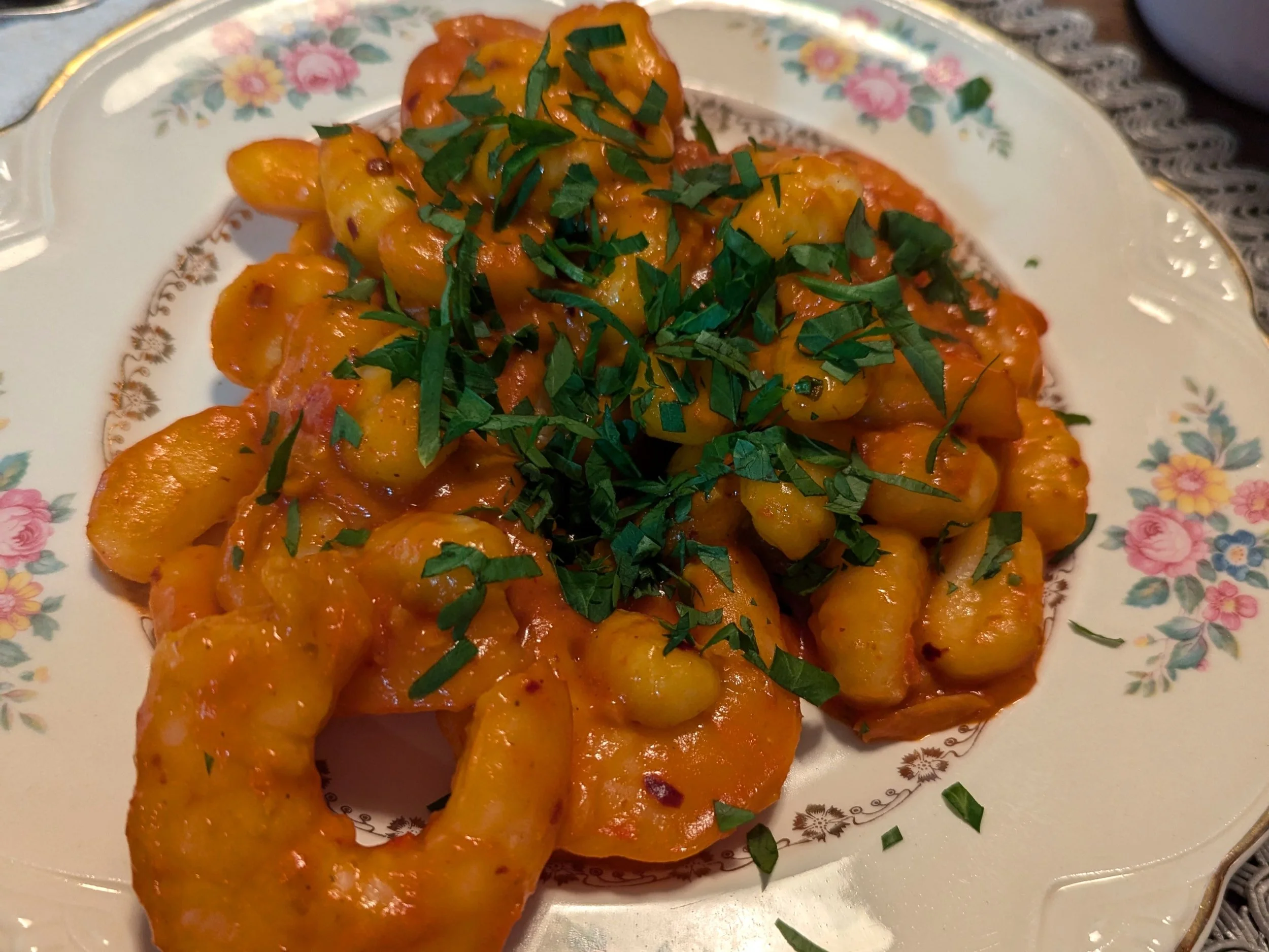 Plate of shrimp and gnocchi in red sauce, garnished with parsley.