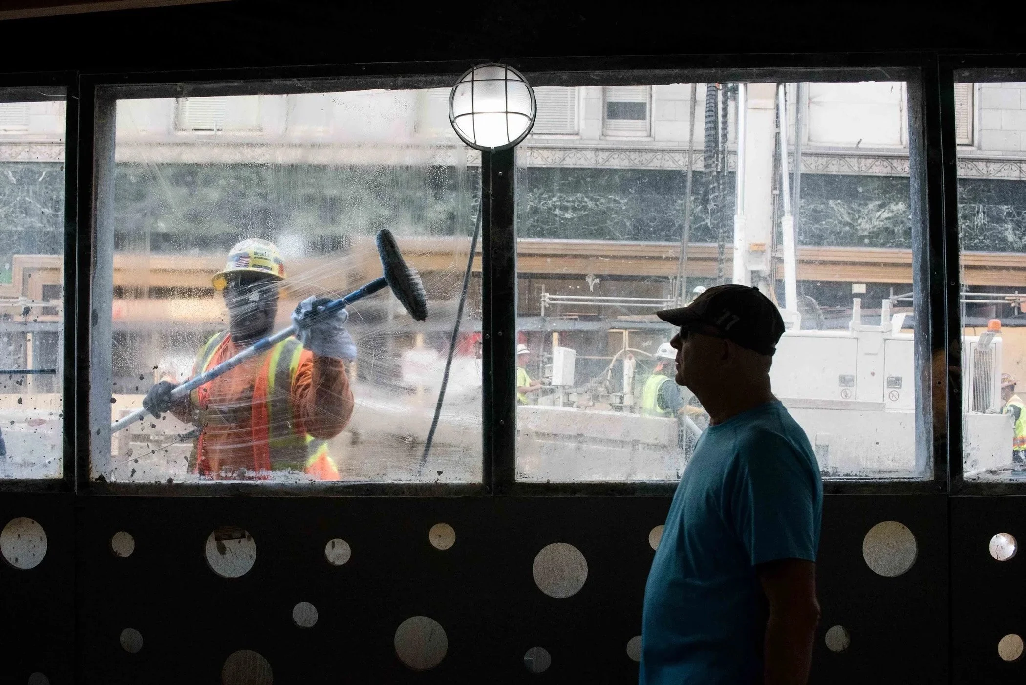 A worker cleans dirty glass as a bystander walks by in San Francisco.