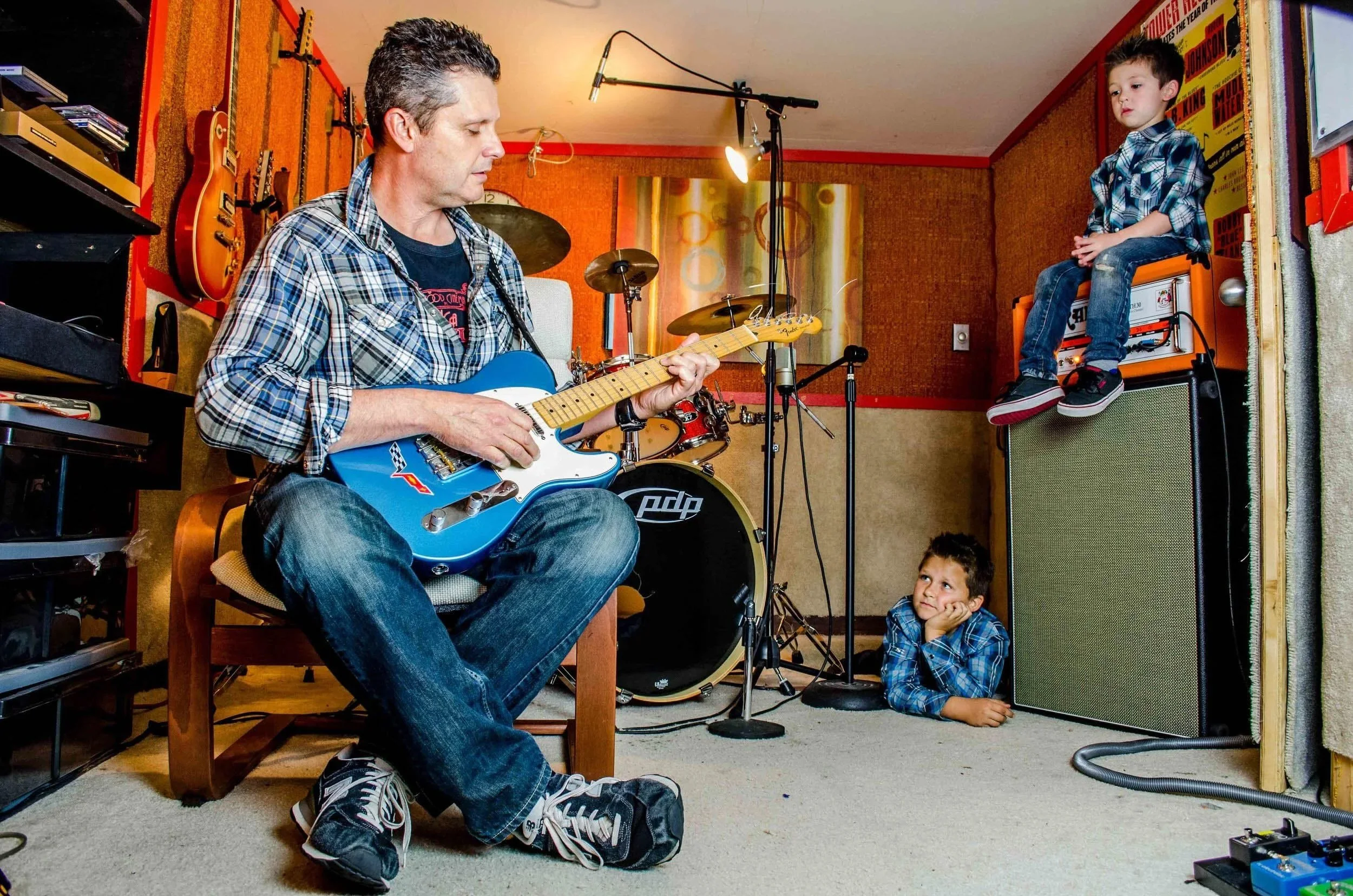 The Sunday Threads guitar player Eric Roemheld plays in his homemade studio while sons Jaden and Blake look on.