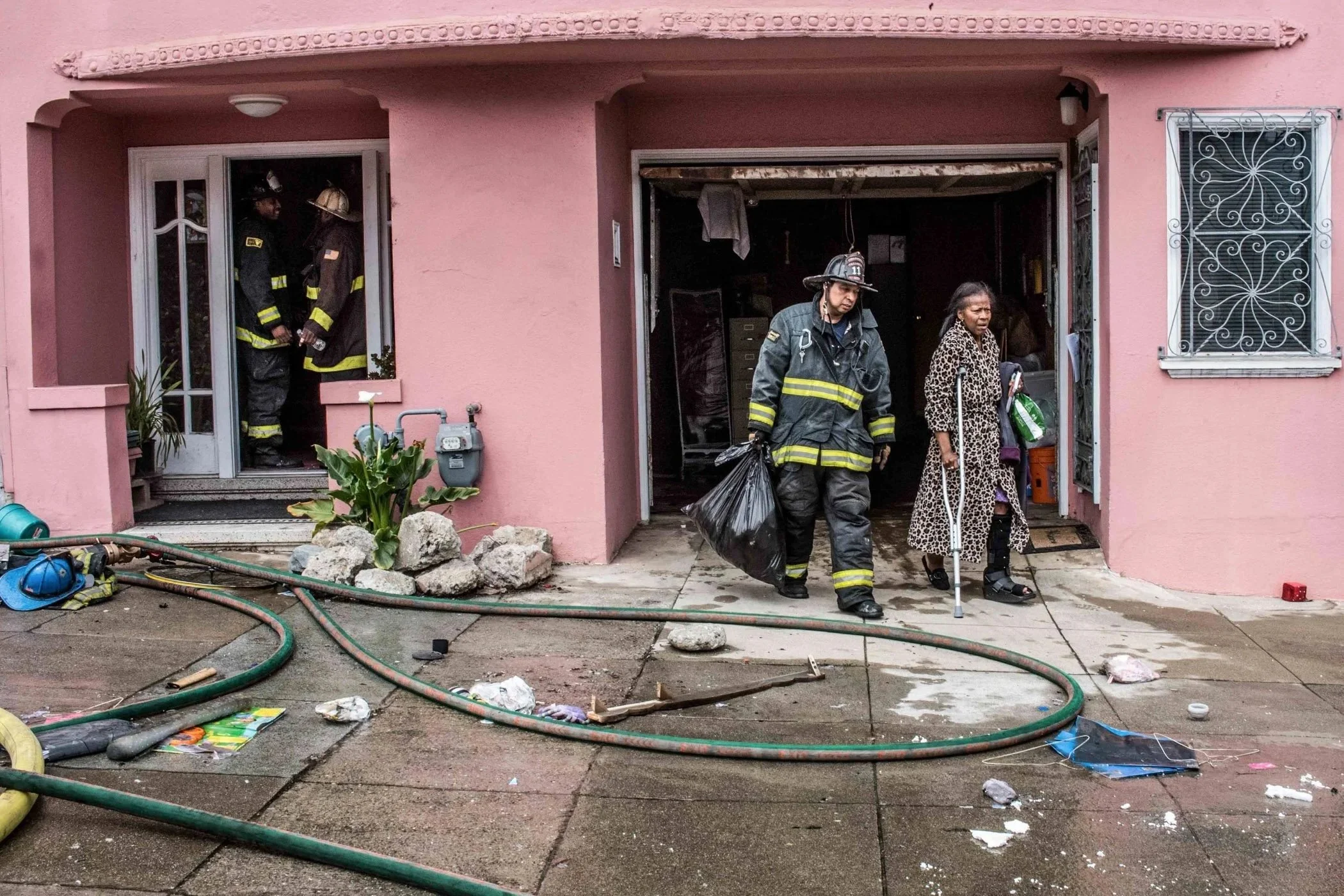 A woman leaves her home while being accompanied by a fireman after her home caught on fire.