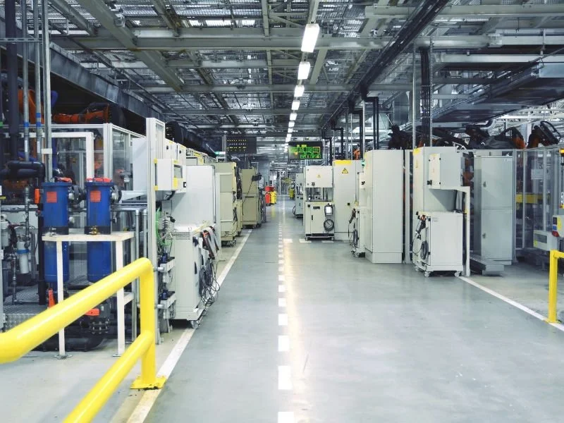 An industrial manufacturing facility with machines and equipment along a central aisle.