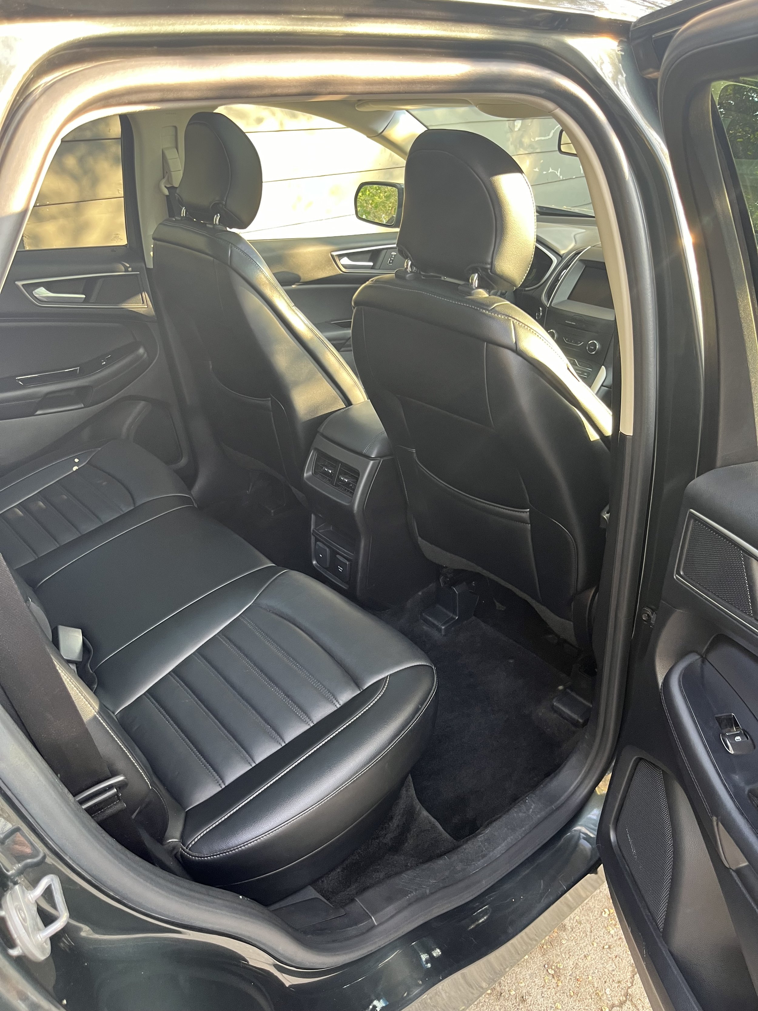 The interior of a black SUV, showing the back seat, front seats, dashboard, and door panels, all with black leather upholstery.