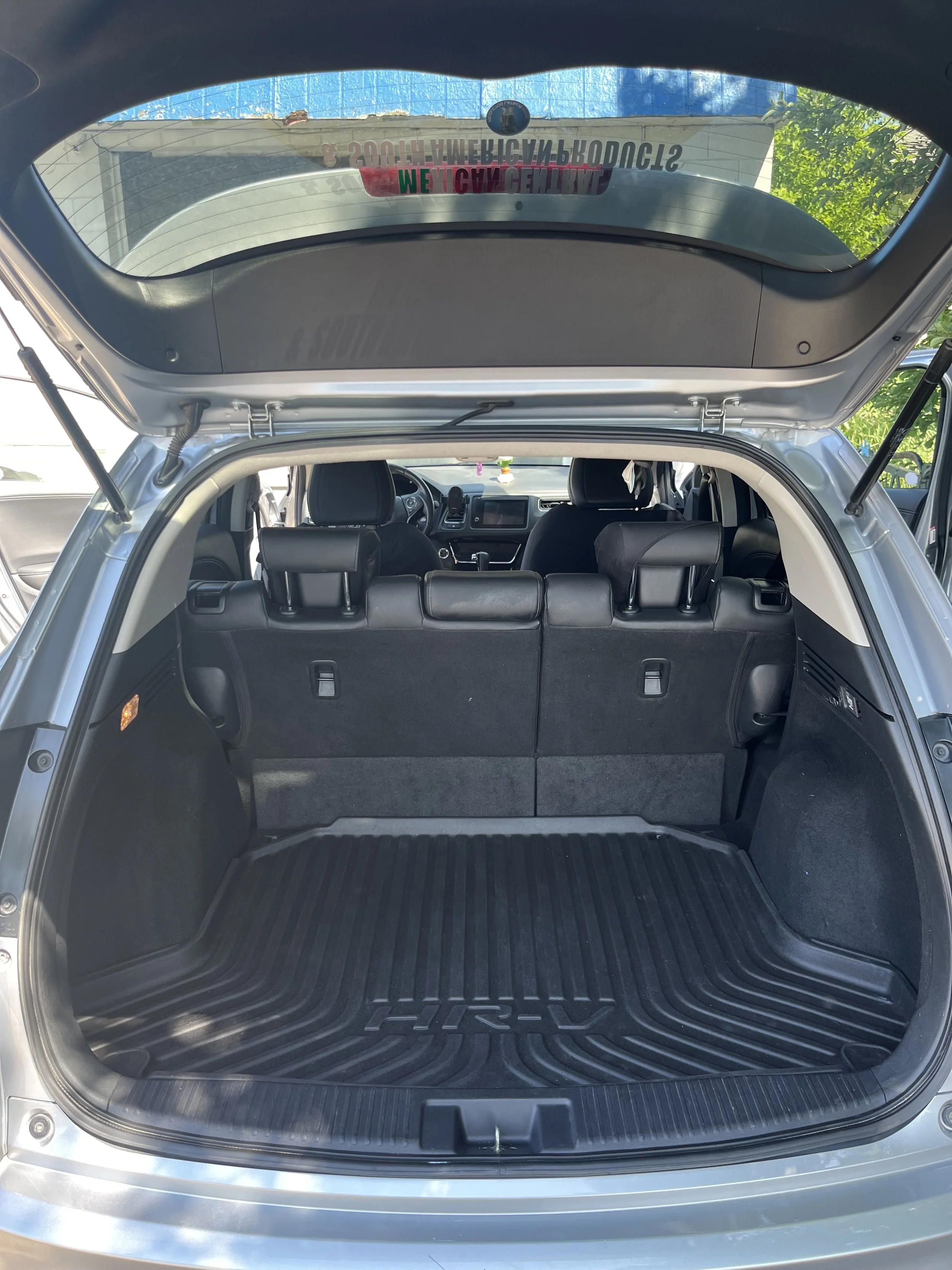 Open trunk of a silver Toyota Hyrux SUV with a black rubber cargo mat inside, showing the rear seats and the interior dashboard of the vehicle.