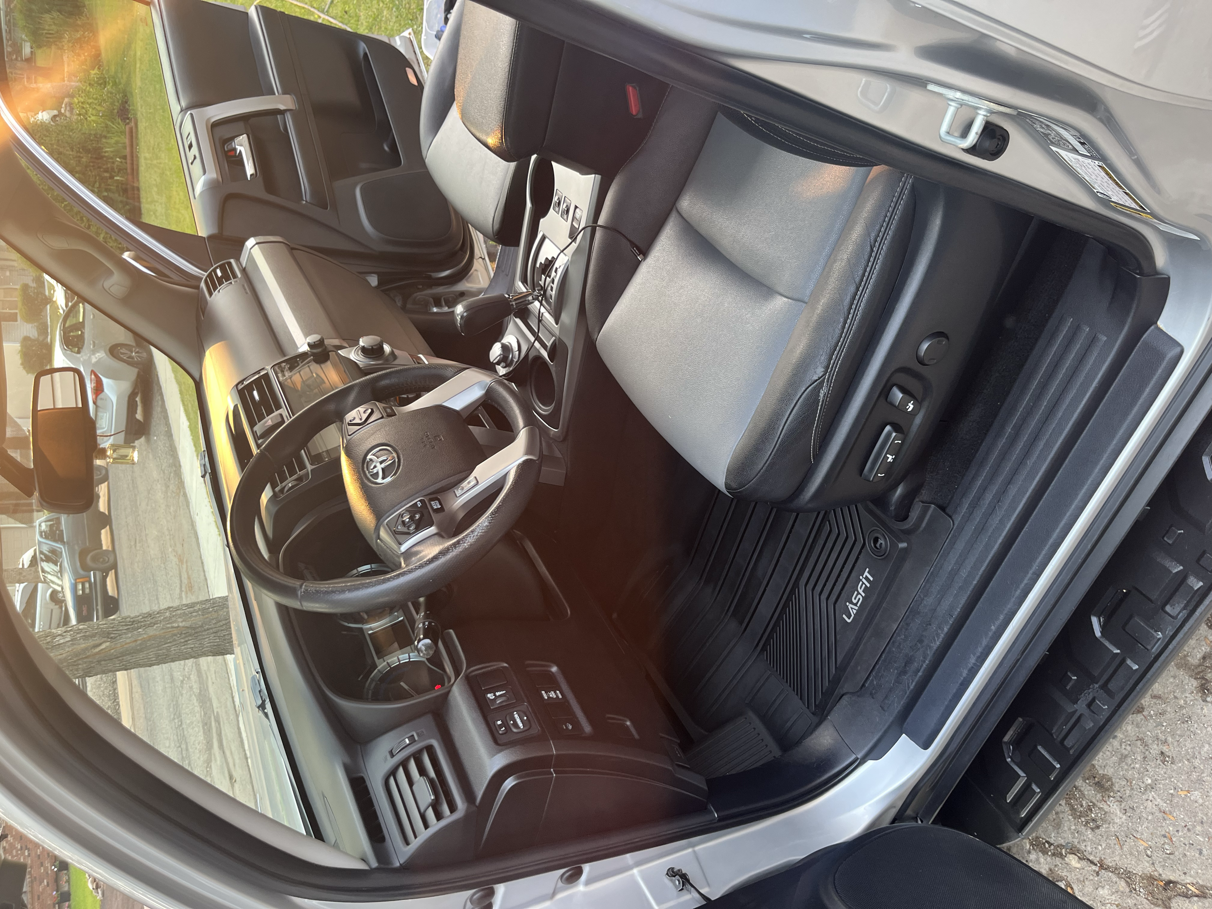 Interior of Toyota van showing dashboard, steering wheel, driver seat, floor mat labeled 'Unifirst', and driver's side door.