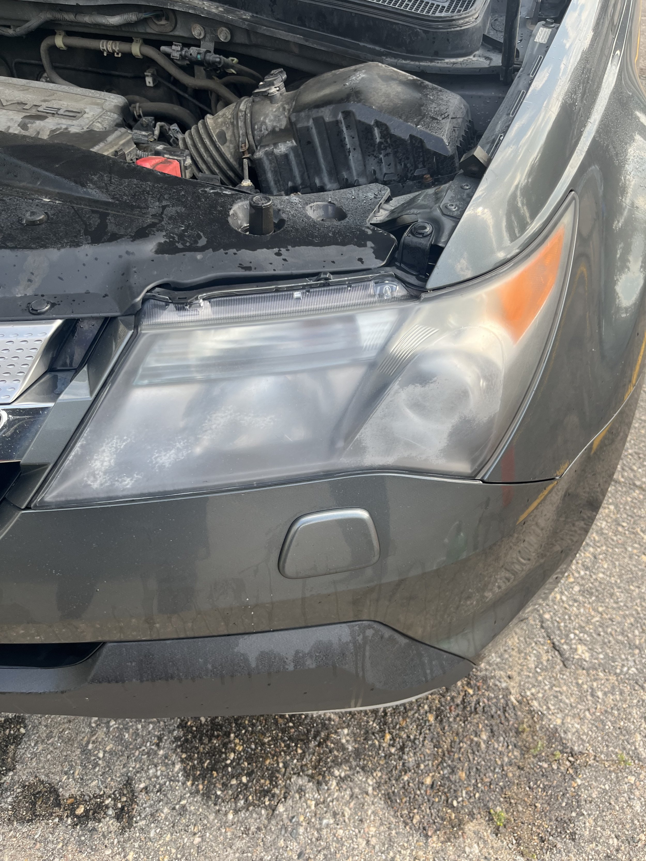 Picture of a drive's side headlight of an Acura SUV before the headlight restoration procedure.