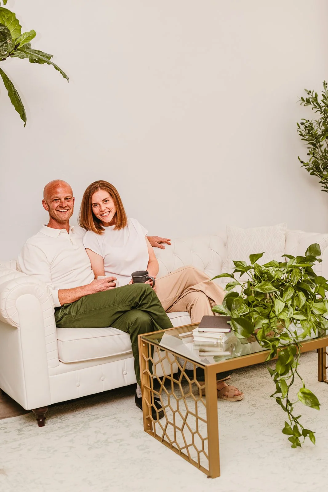 Owners of Ponce Payroll, a company offering payroll services for small businesses, sit on a white couch smiling and drinking coffee