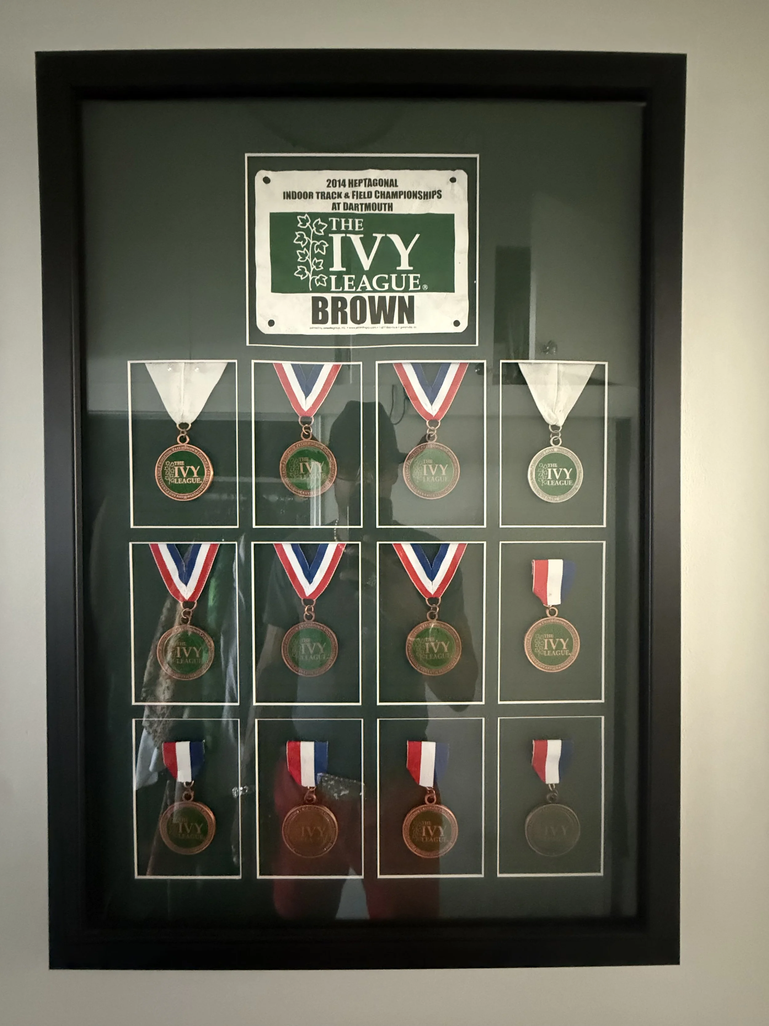 Display case with medals from the 2014 Heptagonal Indoor Track & Field Championships at Dartmouth, part of the Ivy League, featuring medals for Brown University.