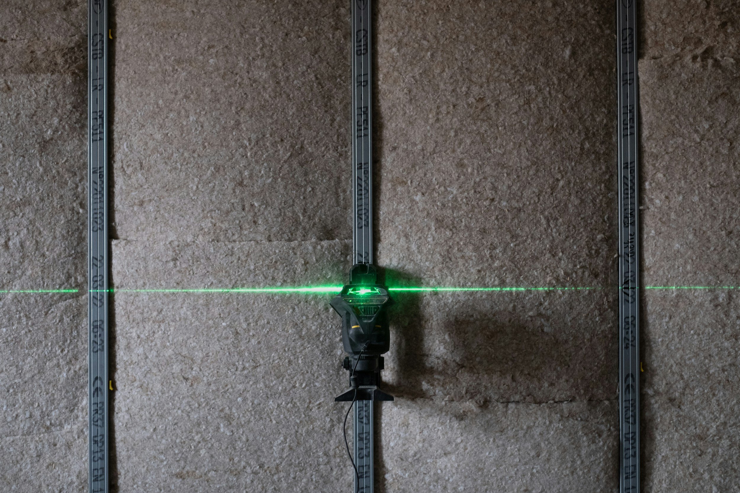Schallschutz, die horizontal durch die Mitte eines Messgeräts auf einer Steinwand scheint, mit vertikalen Metallmessleisten an beiden Seiten.