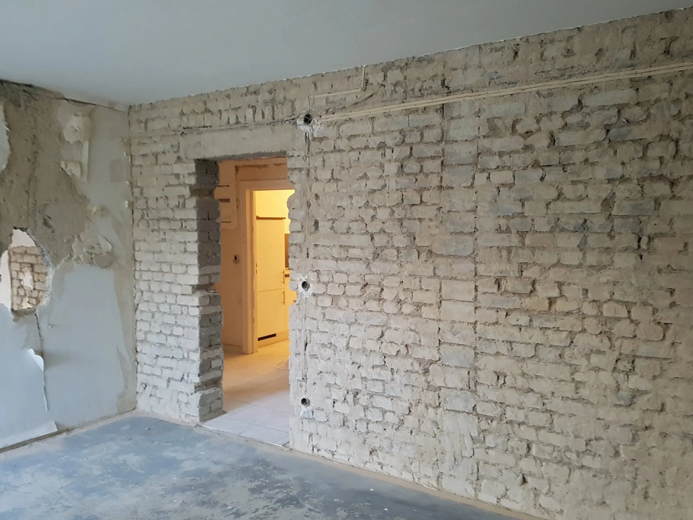 Rohbau einer Wand in einem Gebäude mit sichtbarem Ziegelmauerwerk und unvollständiger Verputzung
