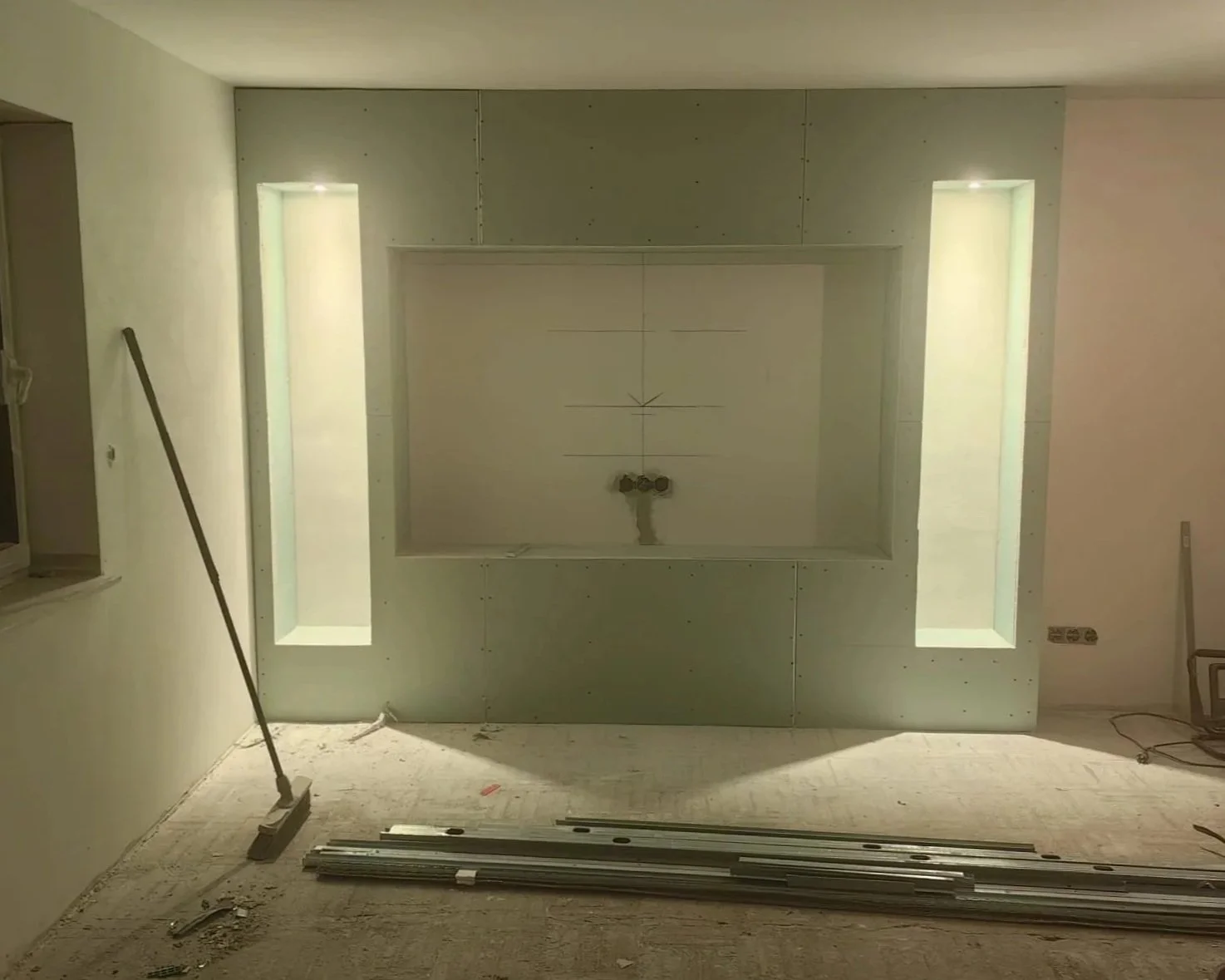 Innenraum eines Hauses im Bau, mit Beaufsichtigung an Wänden und Boden, sowie Bauspachtel und Baumaterial auf dem Boden.