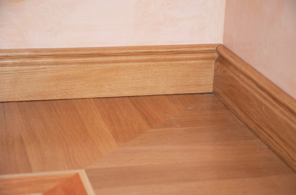Boden- und Wandleisten aus Holz in einem Zimmer mit Holzboden.