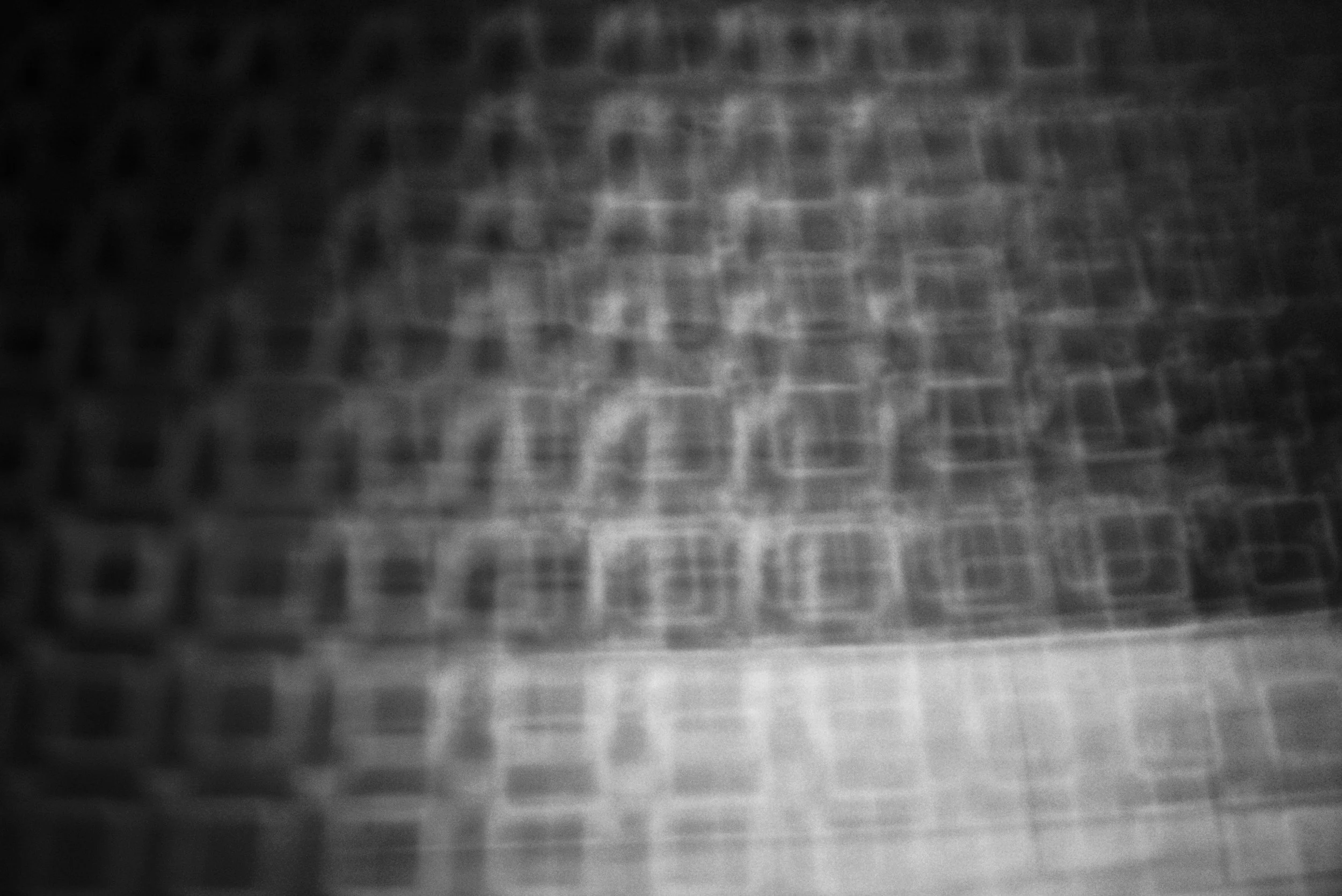 Close-up view of a textured surface with a grid pattern, possibly fabric or a patterned material in grayscale.