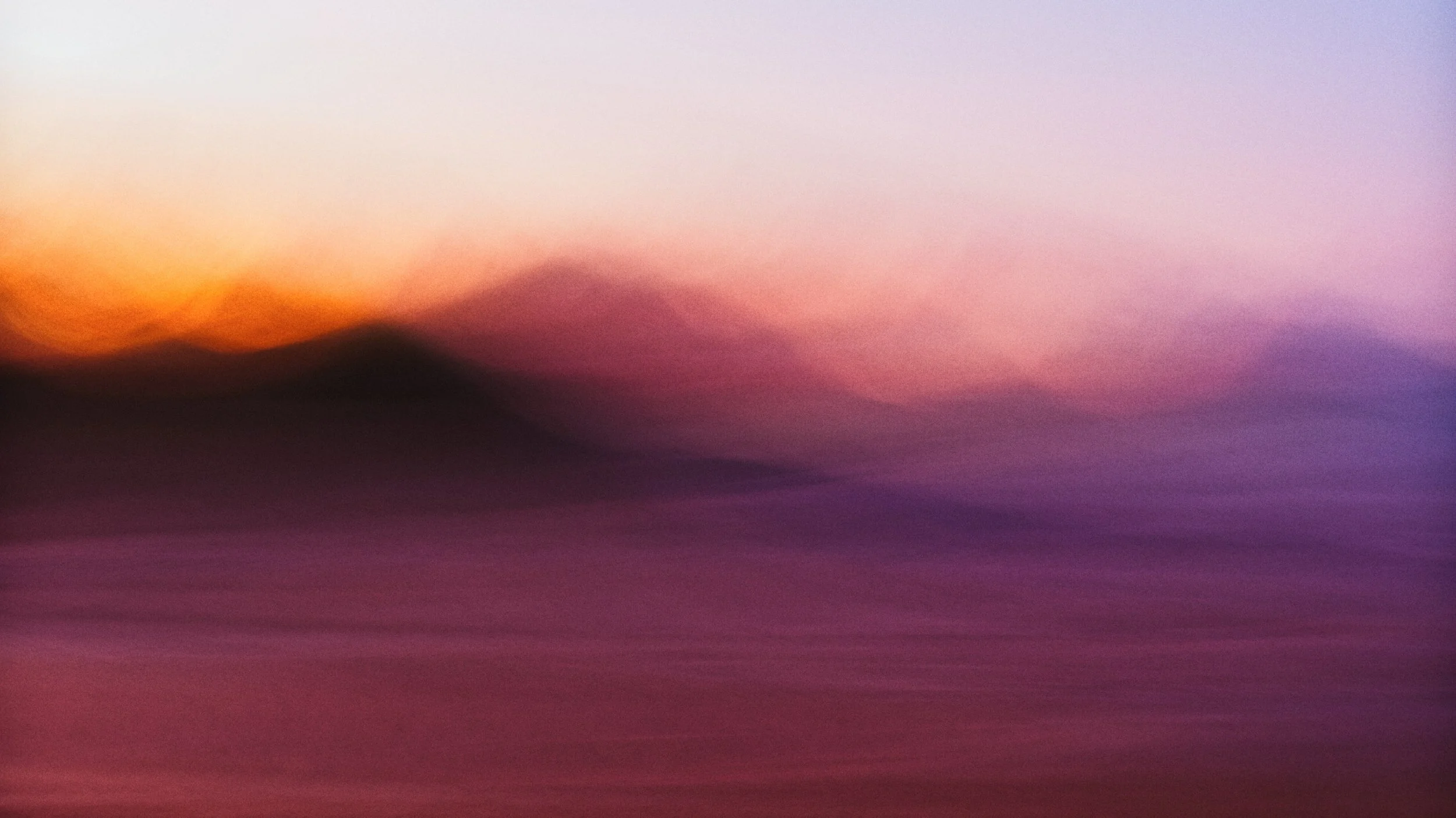 An abstract, colorful gradient background with shades of purple, pink, orange, and yellow blending together smoothly.