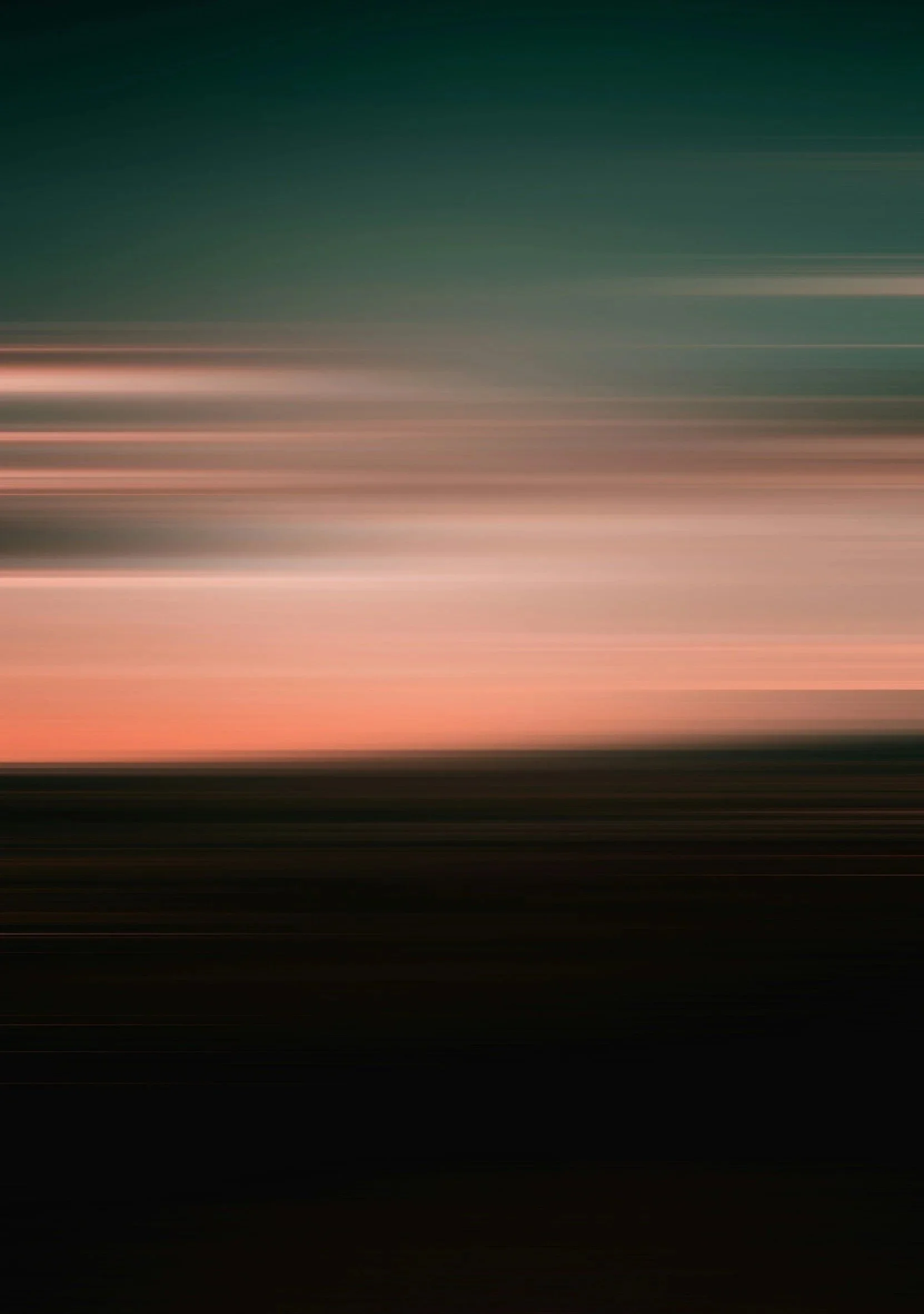 Blurred motion of a landscape during sunset or sunrise with soft pink, orange, and green hues.