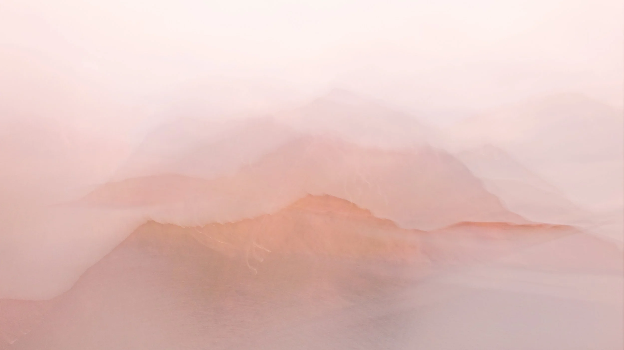 A misty mountain landscape at sunrise with soft pink and purple hues.