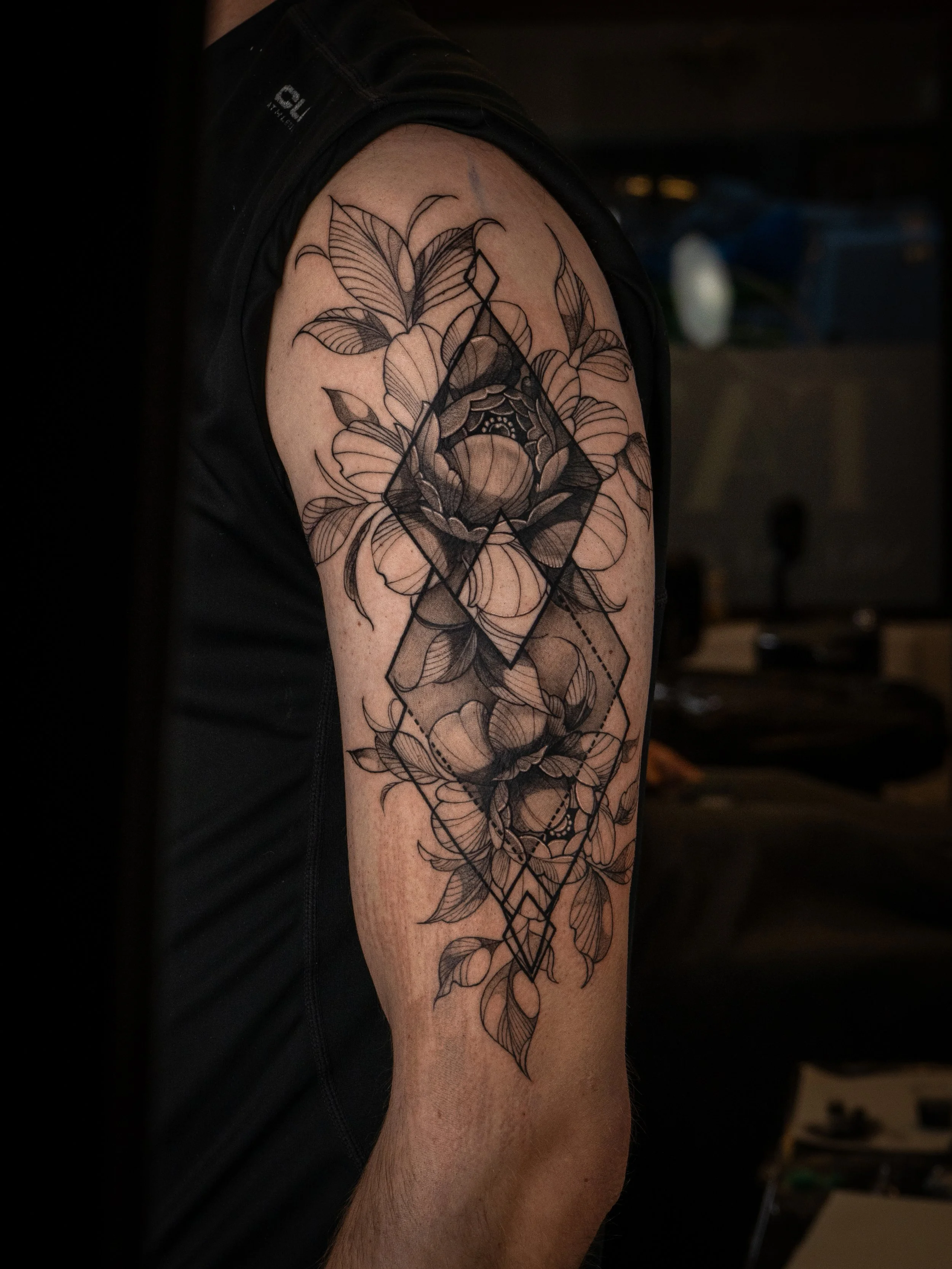 Tatuering av blommor och geometriska former på en persons överarm.