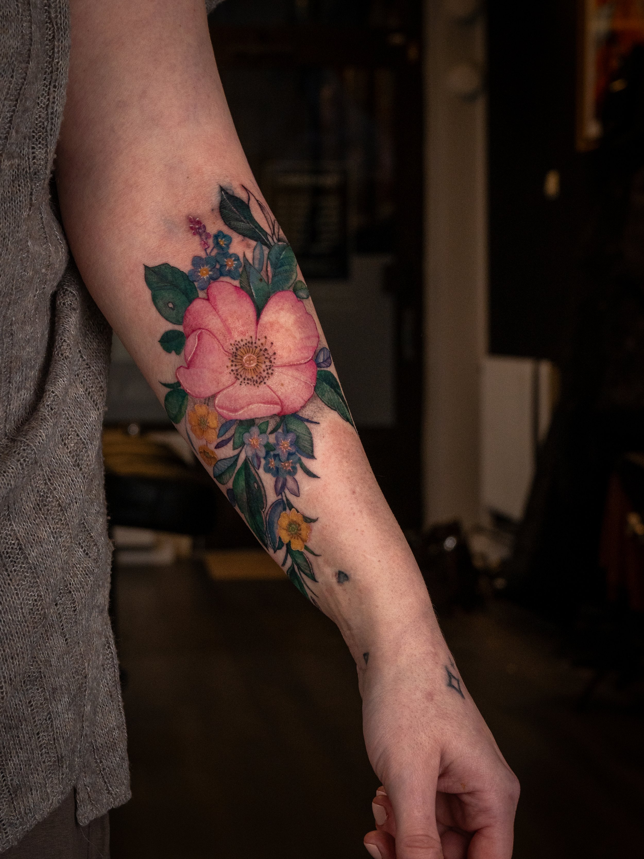 Färgglad tatuering av blommor på en persons arm.
