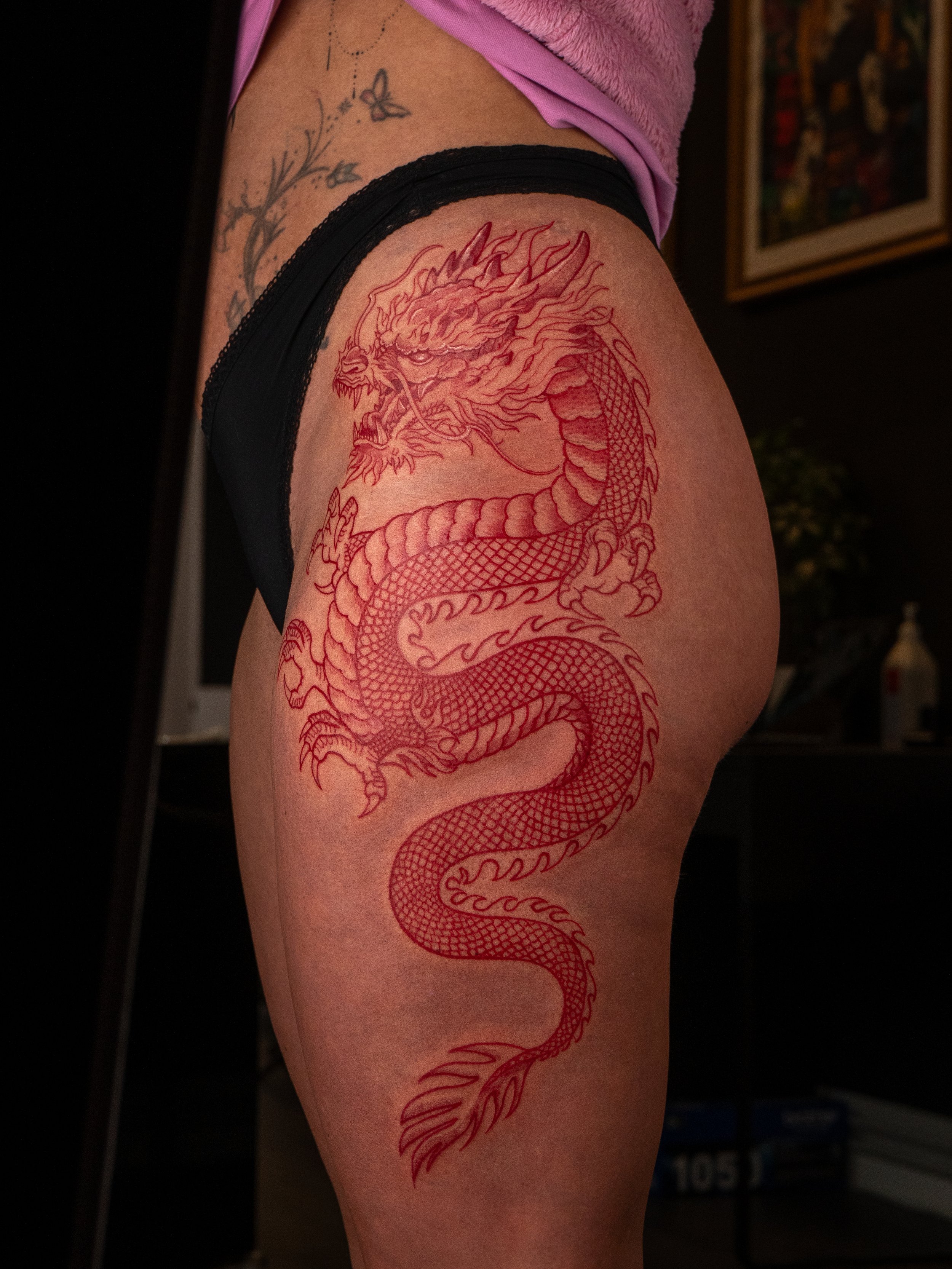 Tatuerad drak på person's lår.