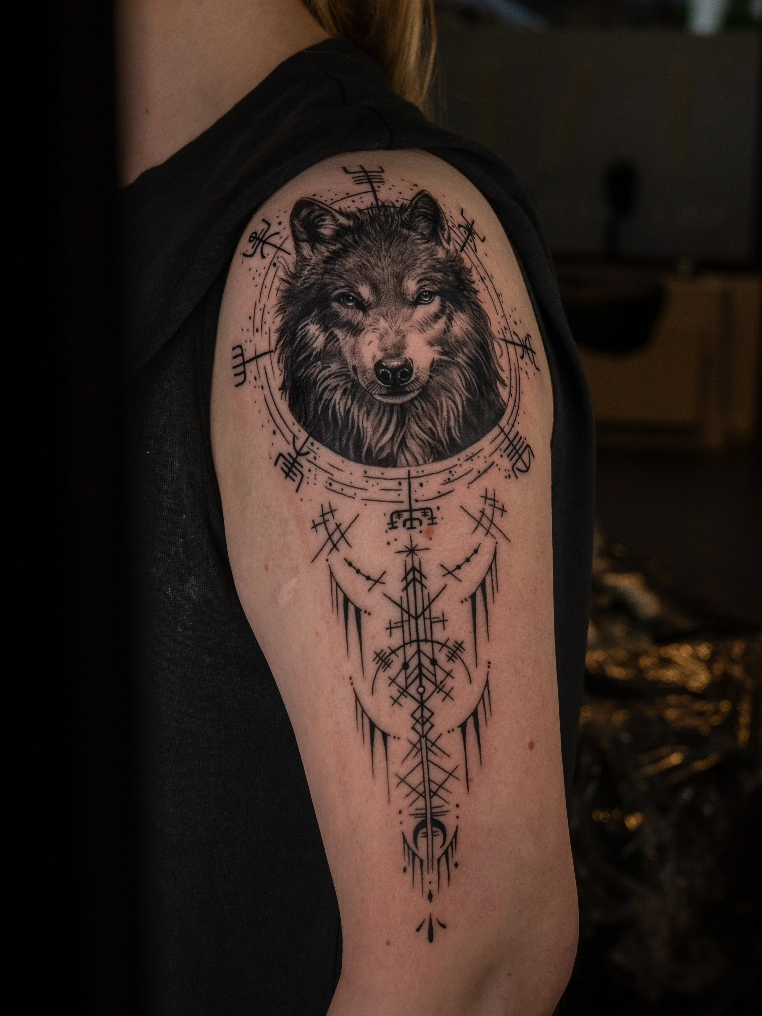 Tatuering av en varg med geometriska och abstrakta dekorationer på överarmen.