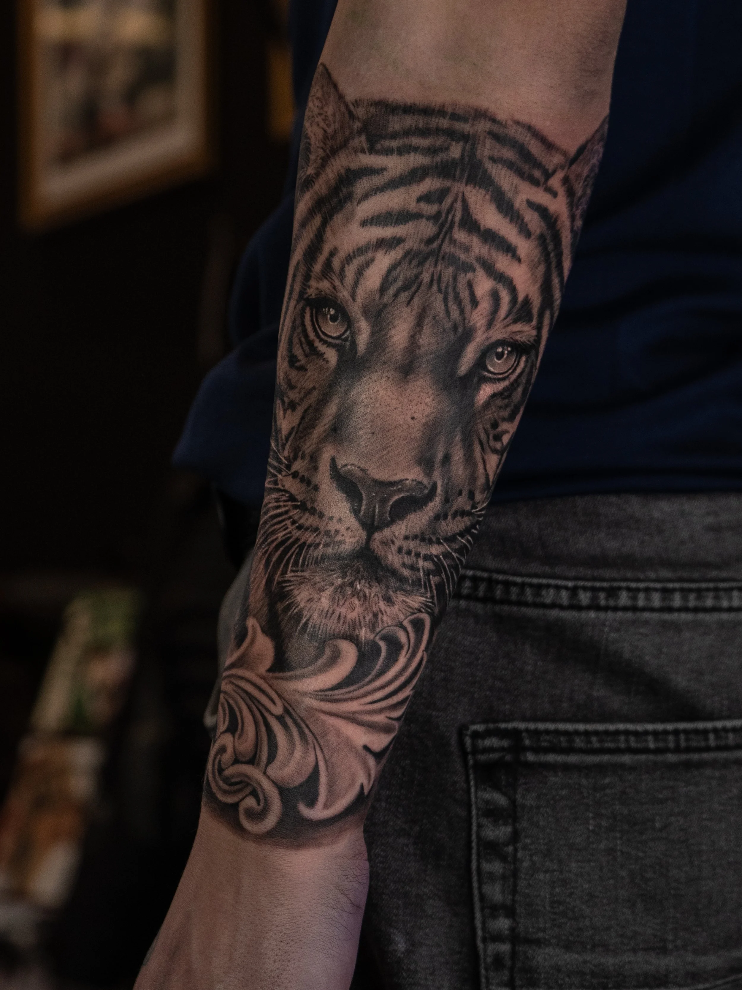 Tatuering av en tigerhuvud på en persons underarm, med detaljrik design och skuggning.