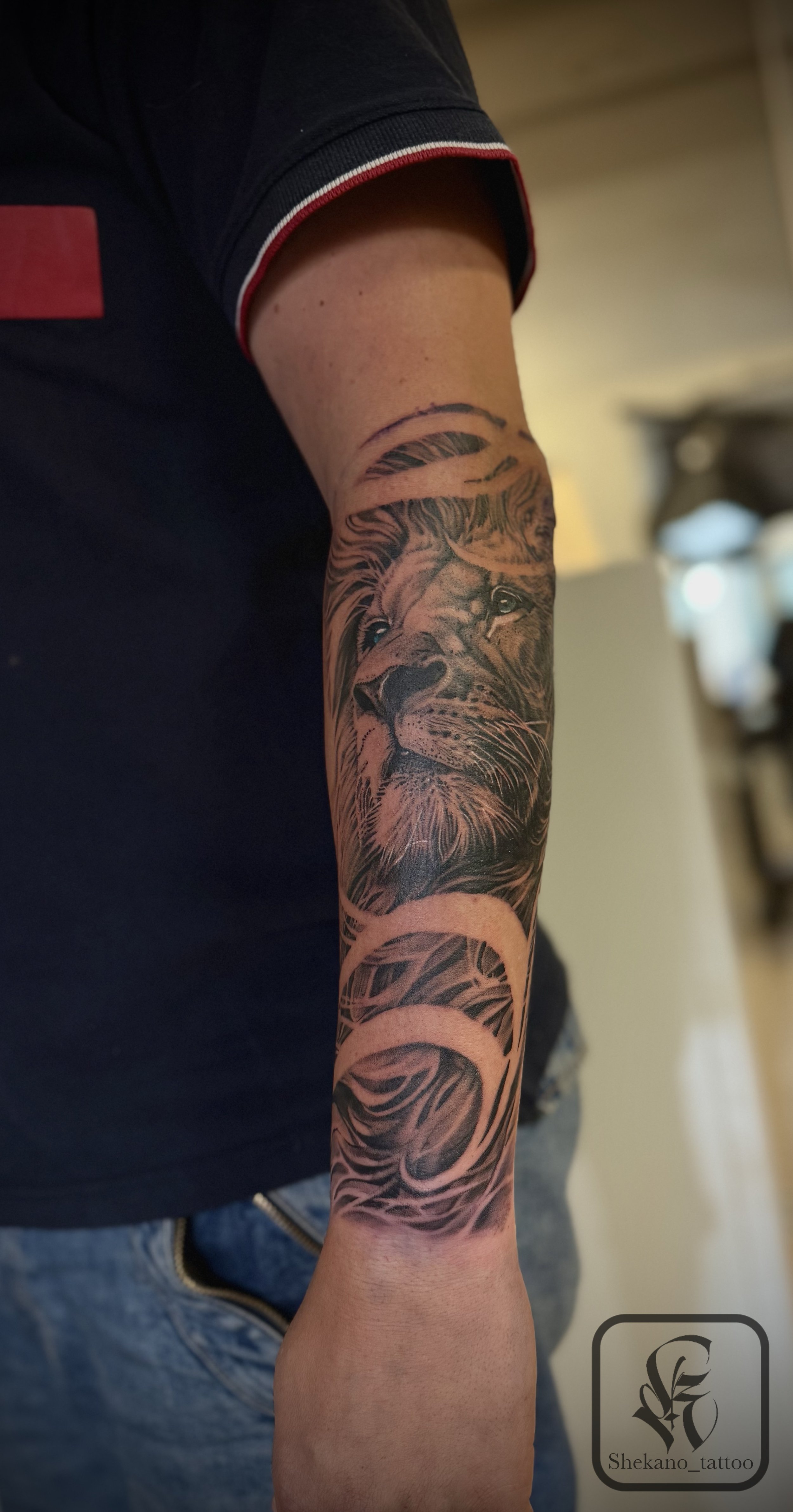 En tatuering av en lejonhuvud på en persons underarm.