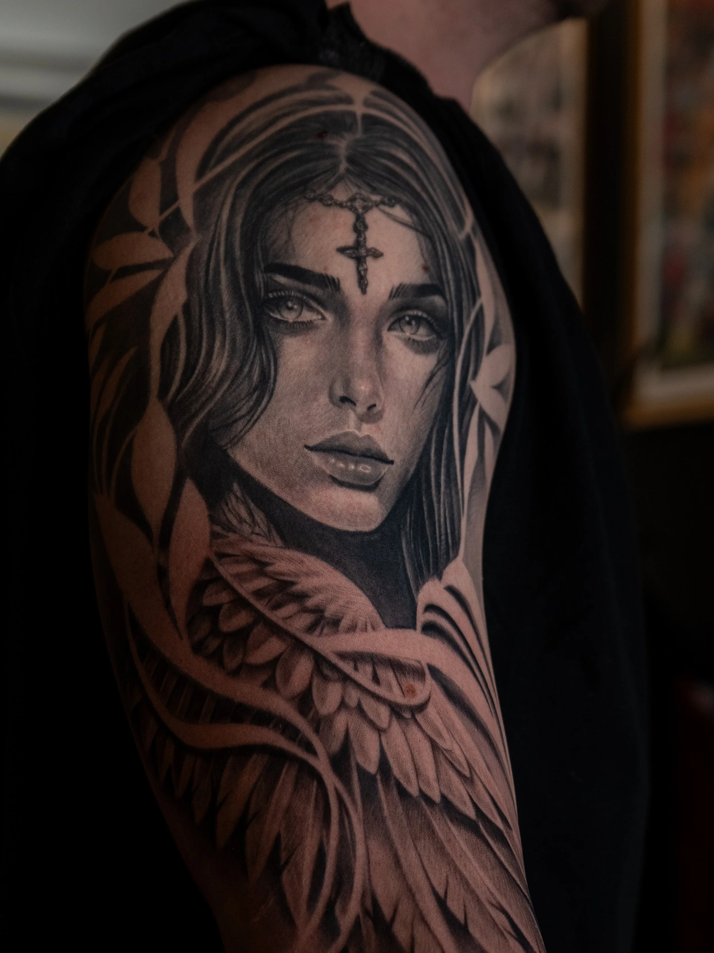 Detaljerad svartvit tatuering av en kvinnas ansikte på en persons övre arm.