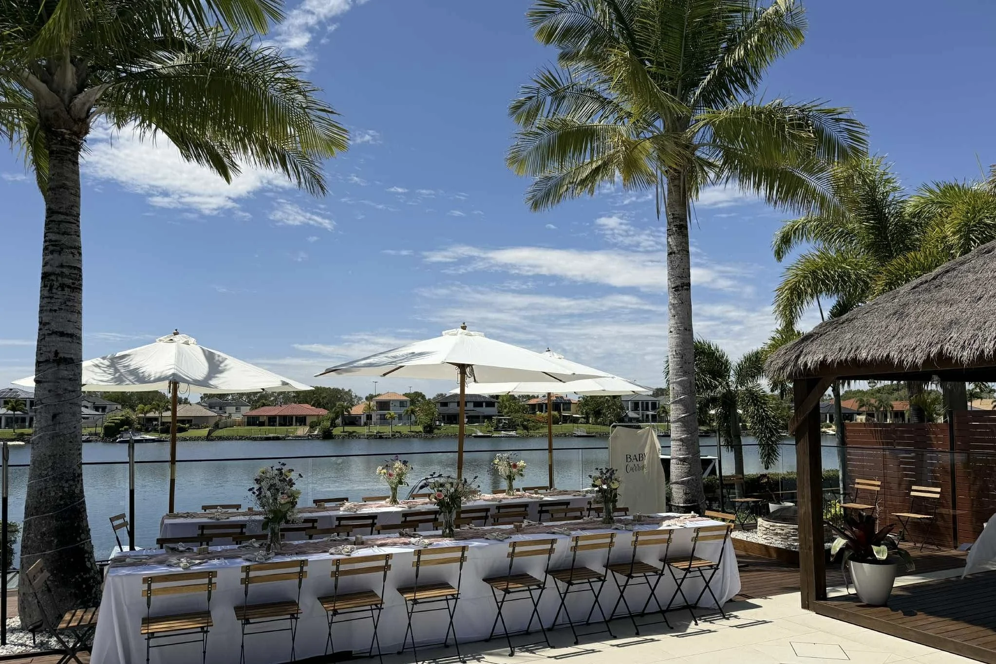 Outdoor baby shower using rustic french bistro chairs, long tables with white linens and white market umbrellas for simple yet elegant look. 